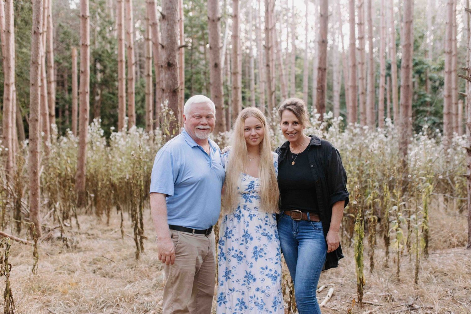 Small group standing together in a wooded area with pine trees.