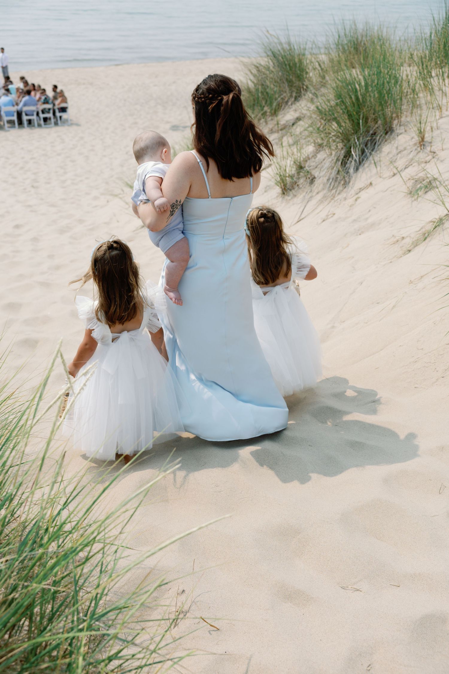 Wedding party members relaxing on a sunny beach dune.