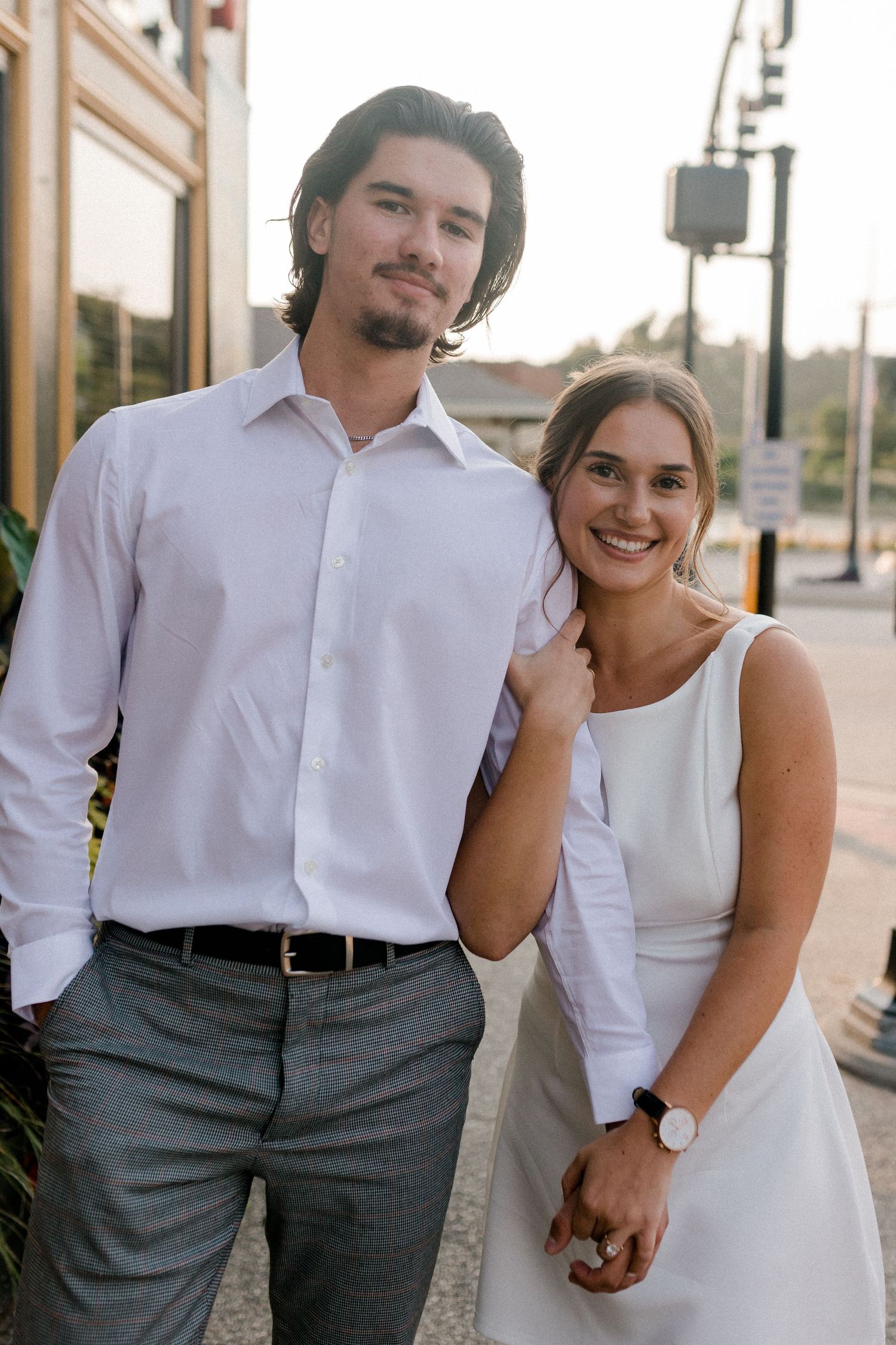 Couple in white and grey formal attire posing together outdoors.
