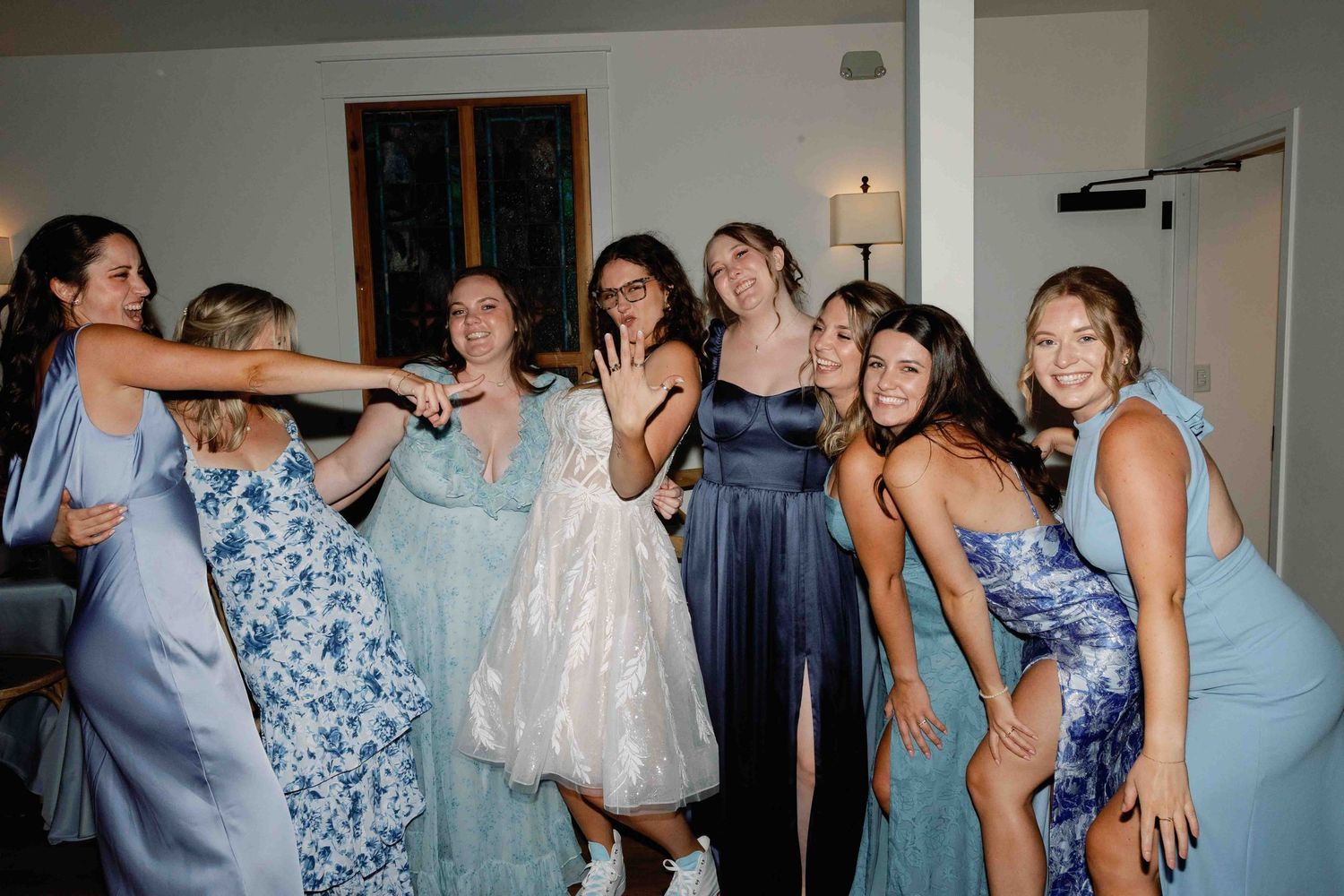 Group dancing and celebrating in matching blue and floral bridesmaid dresses.