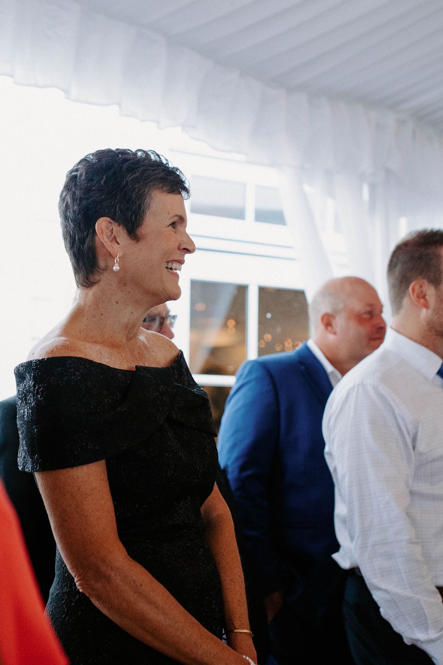 Wedding guests in formal attire mingling at an elegant tented reception.