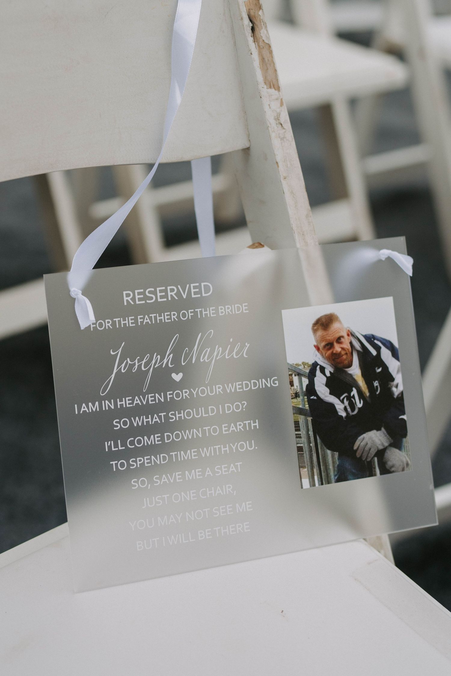 Memorial photo display with sentimental messages and ribbons at a wedding ceremony.