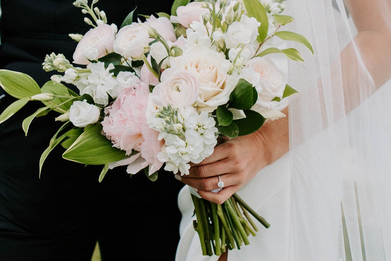 Elegant white and blush wedding bouquet with roses and greenery.