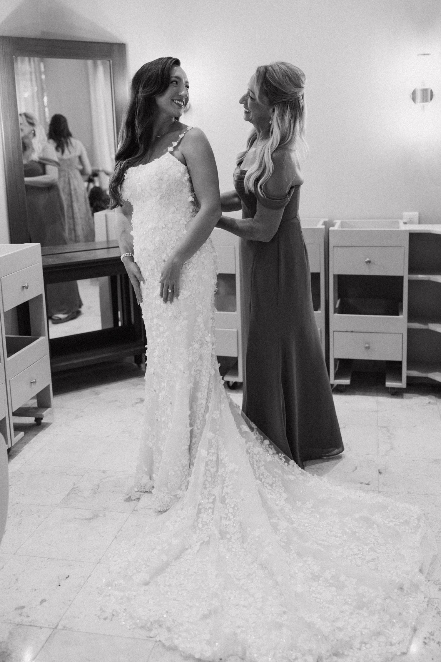Bride in a lace wedding gown gets ready in a bridal suite with bridesmaids.