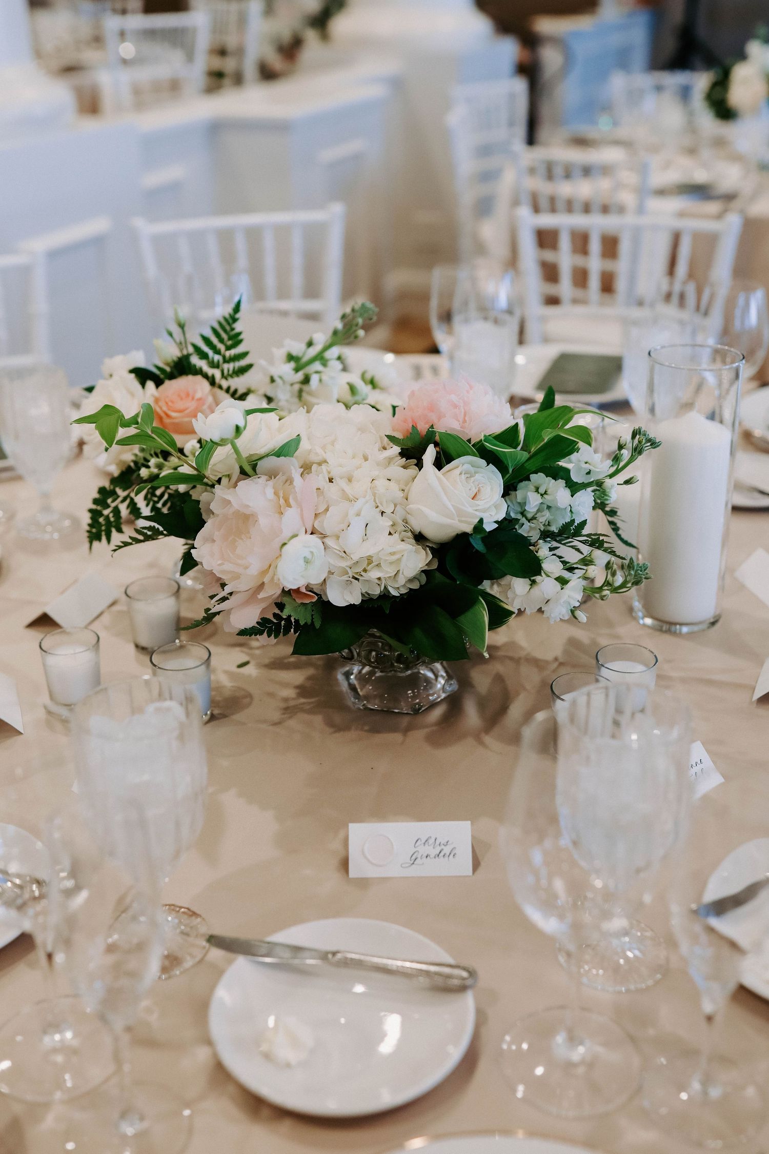 Wedding table decorated with white floral centerpieces and elegant place settings.