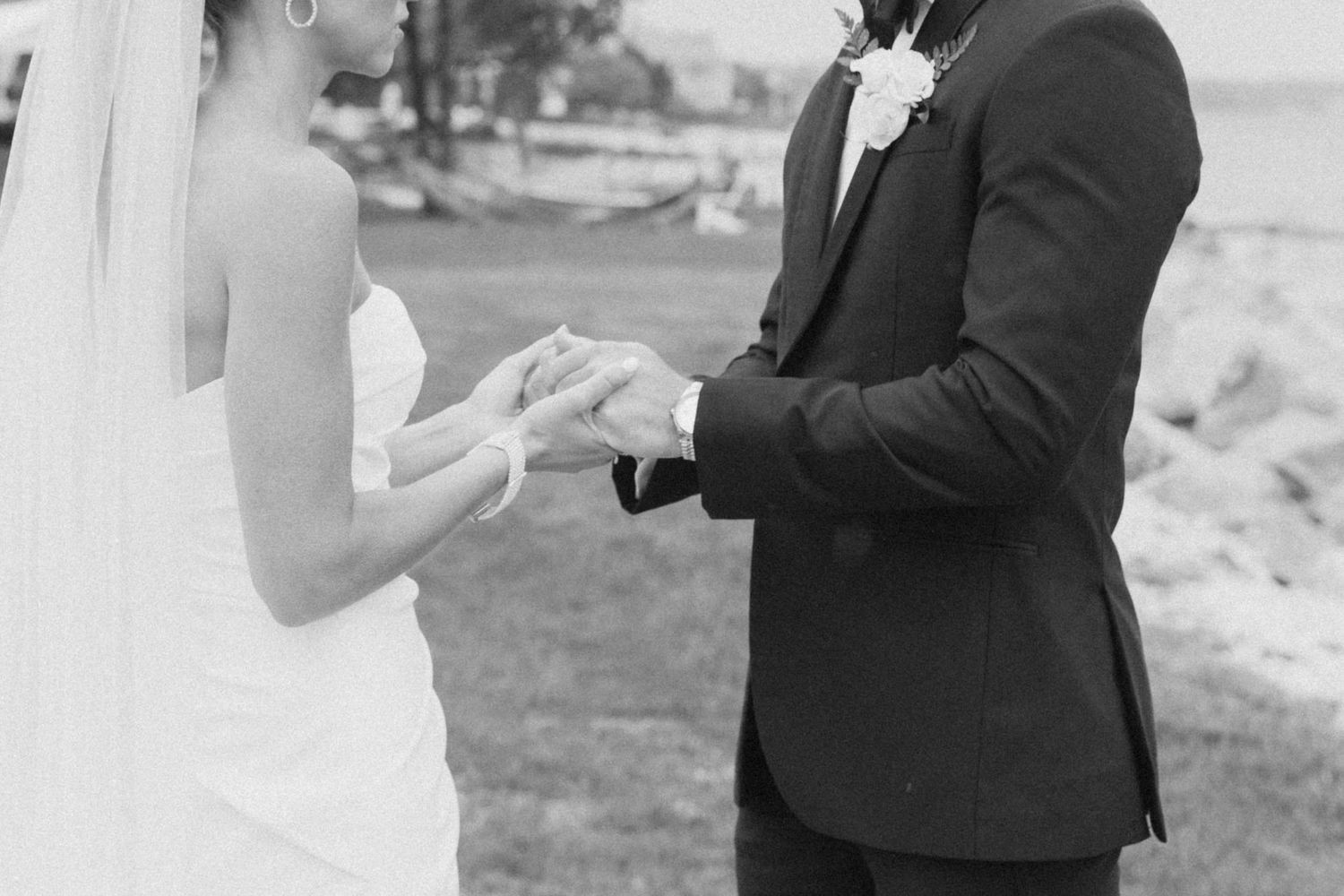 A close-up black and white shot of a couple exchanging rings during their wedding ceremony.