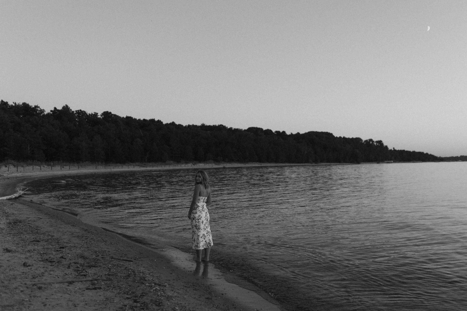 Peaceful beach scene at dusk with dark silhouettes against a dimming sky.