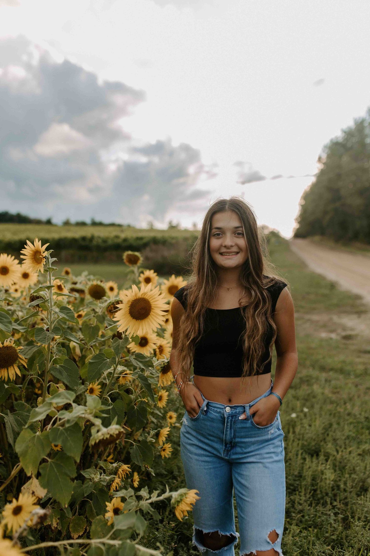 Casual summer portrait session in a blooming sunflower field at golden hour.