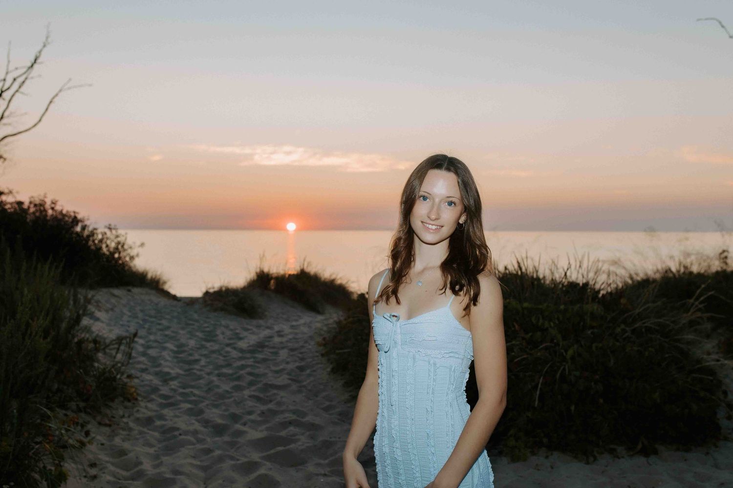 Sunset beach photoshoot with soft golden light and coastal vegetation.