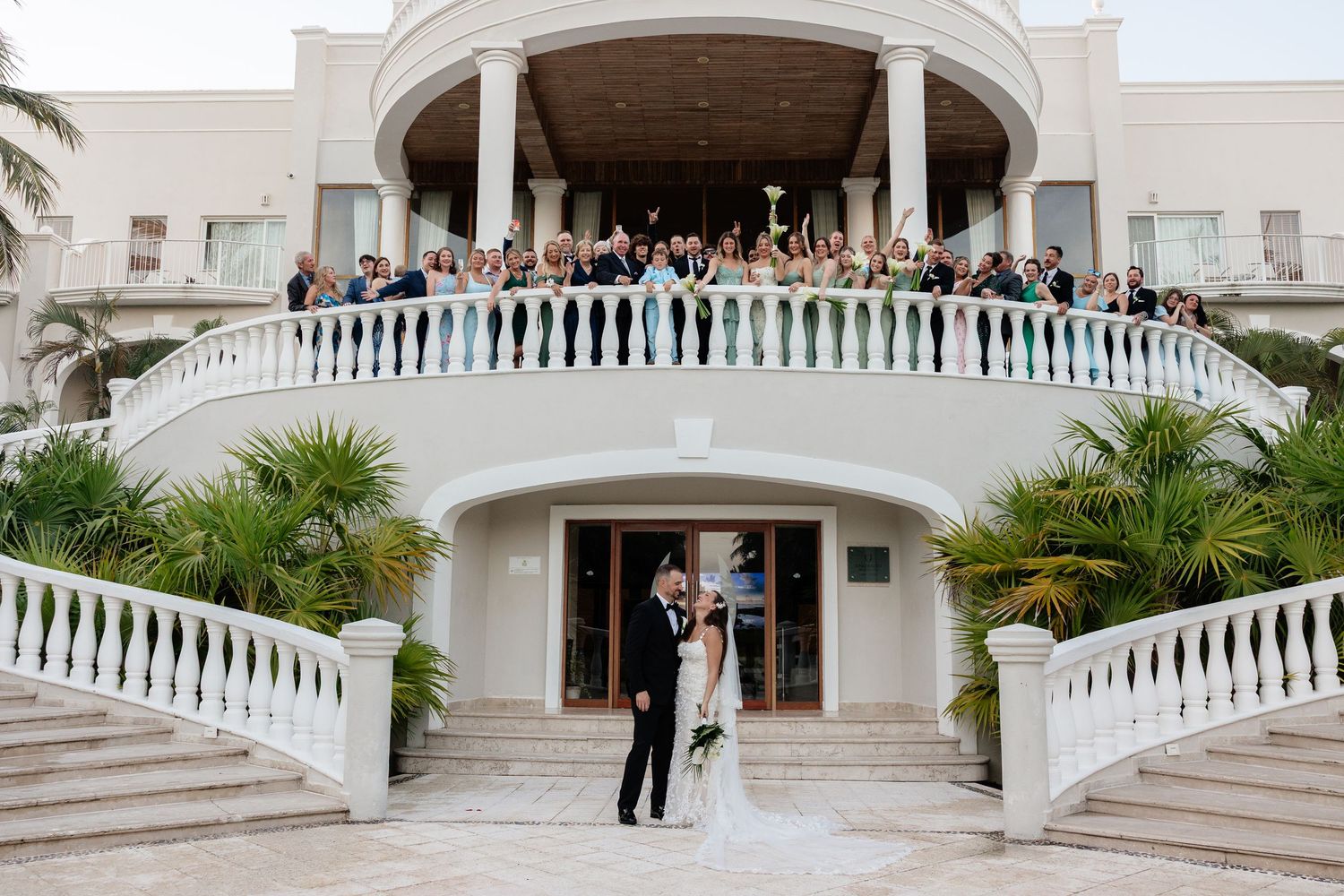 Panoramic view of wedding venue with white colonial architecture and curved staircase.