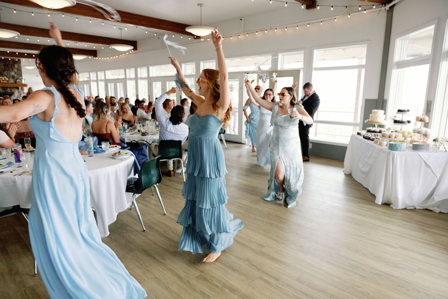 Wedding celebration in a bright reception hall with guests dancing and celebrating.