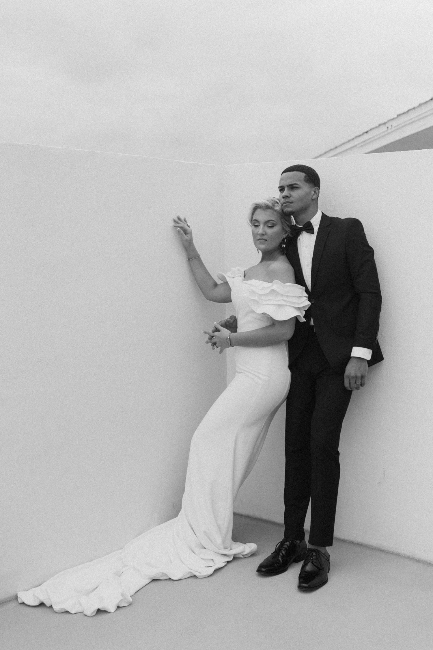 Artistic black and white wedding photos against a minimalist white wall.