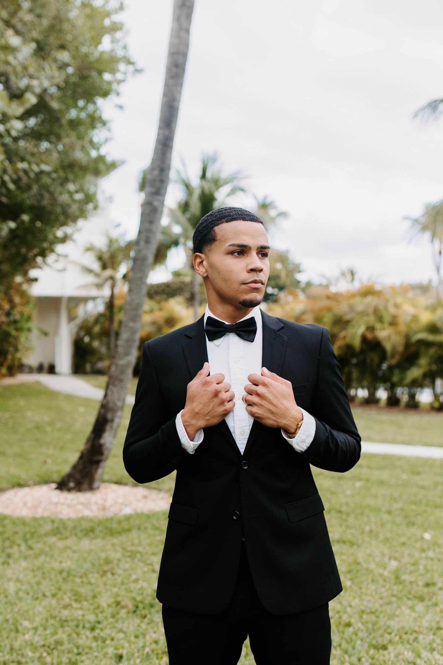 A sequence of someone adjusting their black bowtie and formal attire on a sunny day.