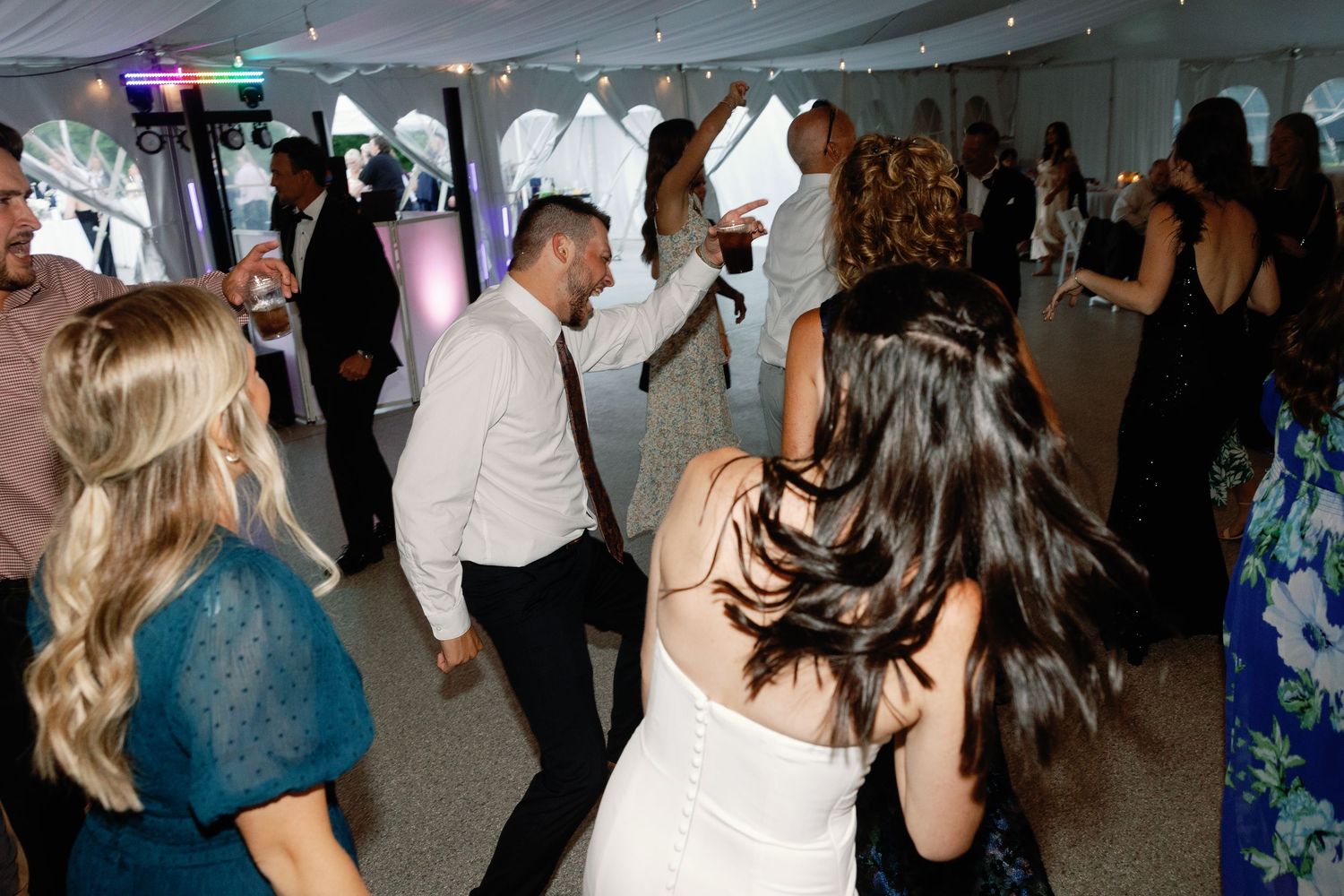 Wedding party guests dancing and socializing at an indoor reception venue.