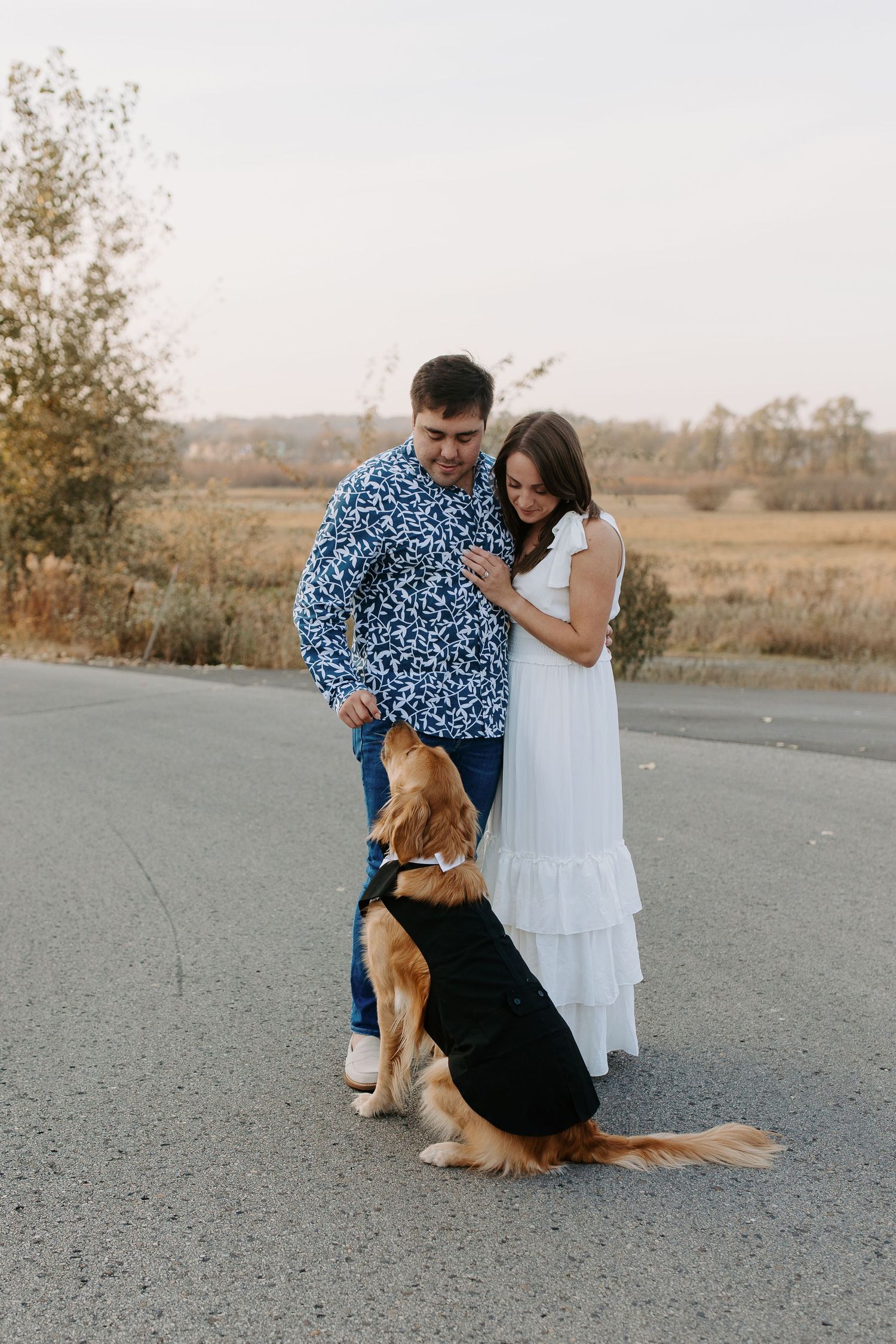 Family photo session featuring a couple posing with their beagle on a country path.