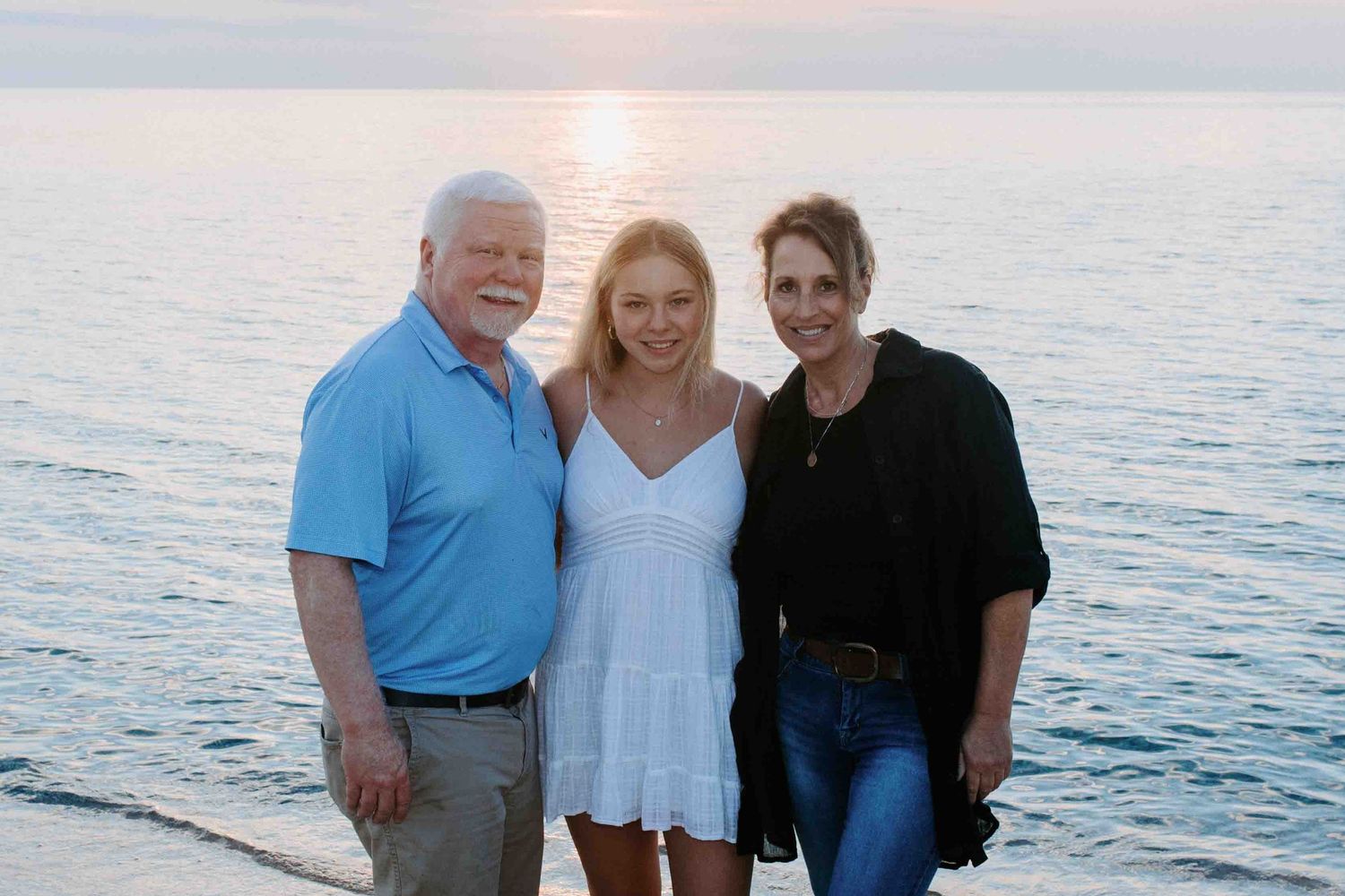 Group of people posing together at sunset by the ocean.