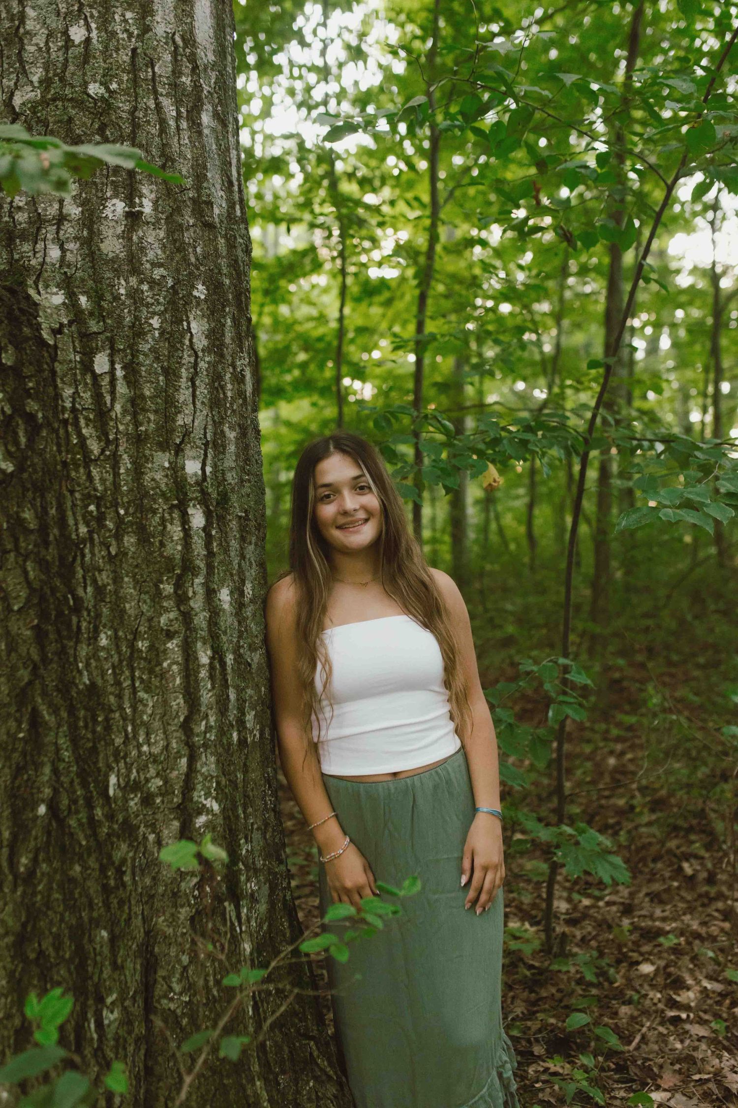 Natural forest photography with white and sage green outfit contrasting against woodland scenery.