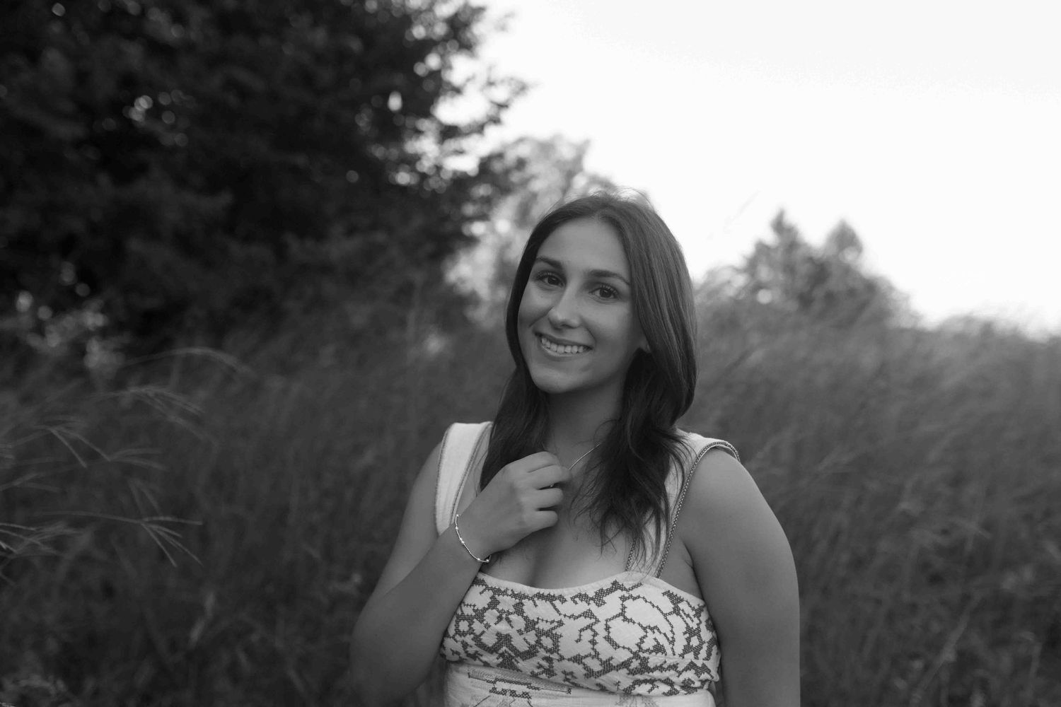 Portrait photo in black and white showing a joyful smile against a natural outdoor background.
