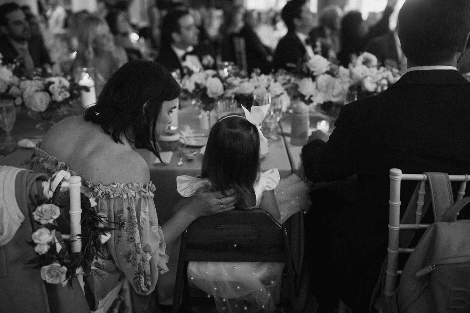 Black and white reception photo showing decorated tables with floral centerpieces and formal place settings.