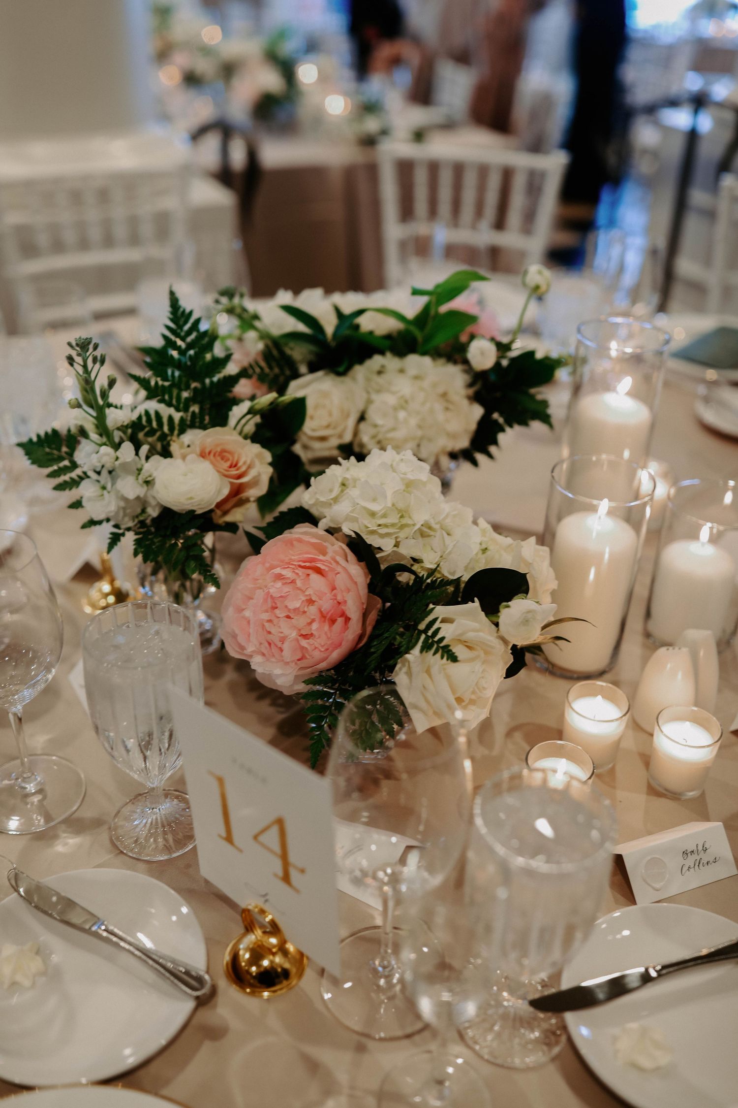 Wedding reception table decorated with pink and white roses, candles, and crystal glassware.