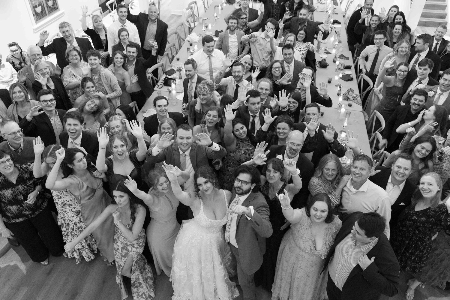 Large group of wedding guests pose together for a celebratory photo.