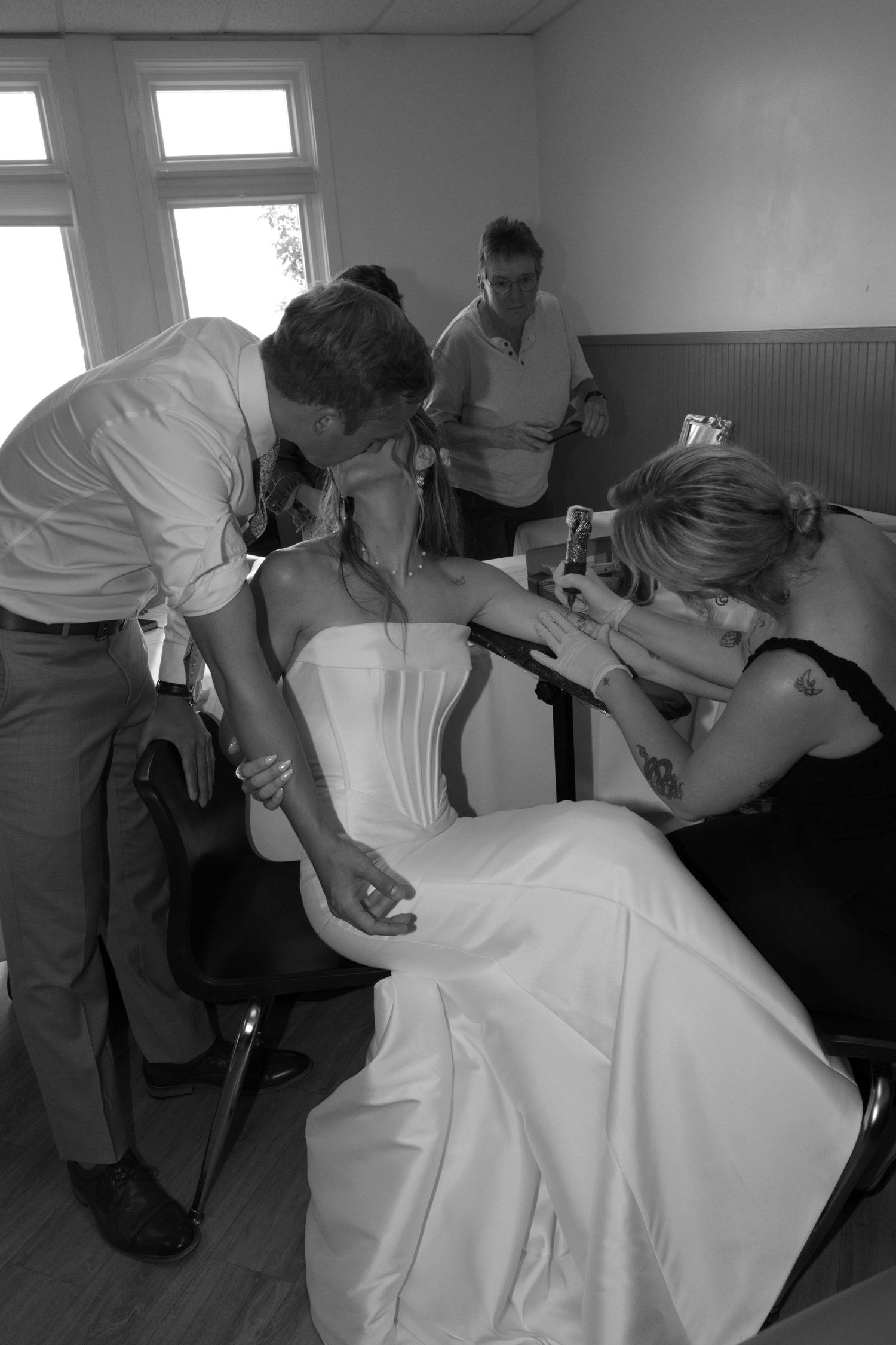 Wedding dress being adjusted and prepared in a bright indoor room.