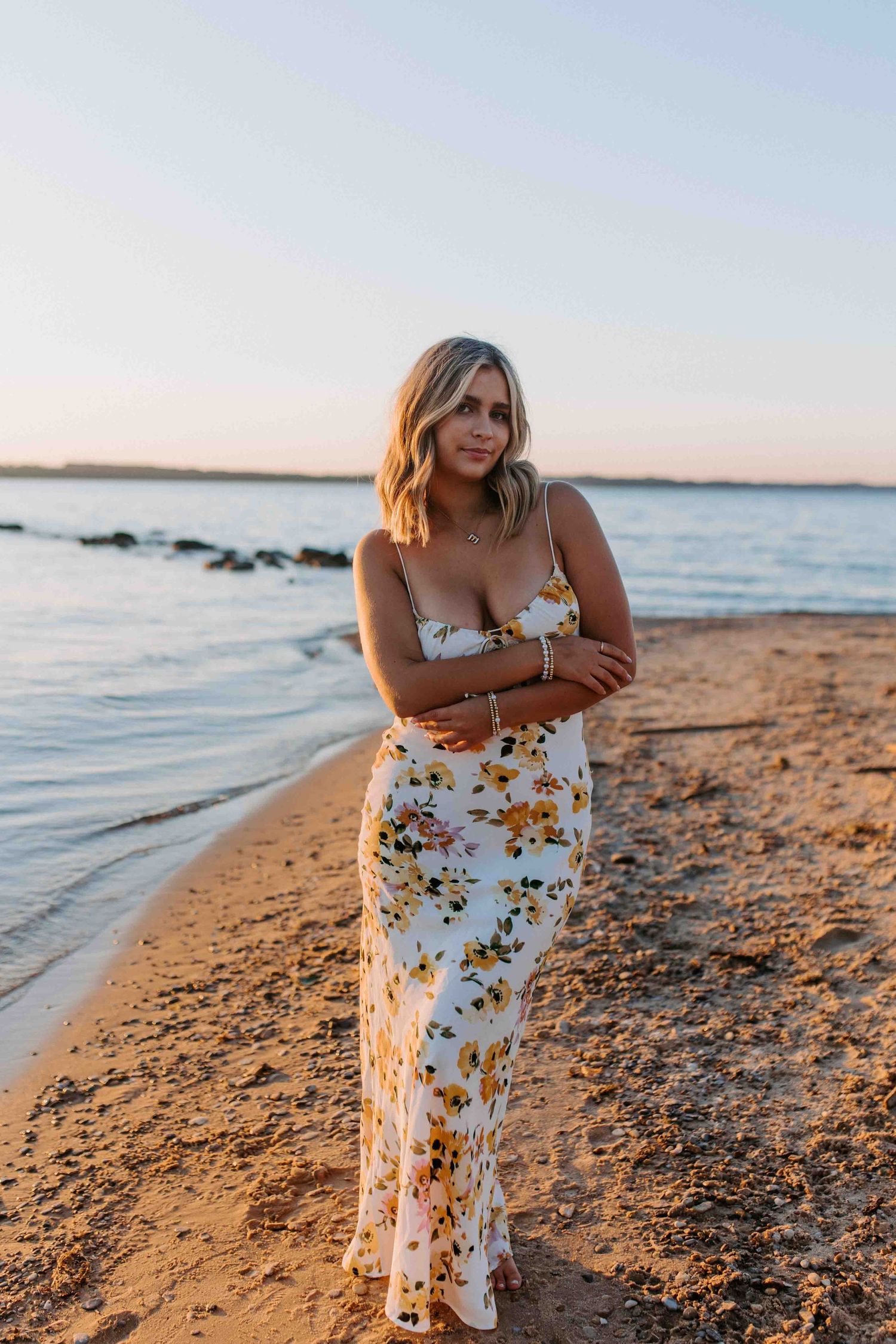 A serene beachside portrait session during golden hour with waves and rocky shoreline.