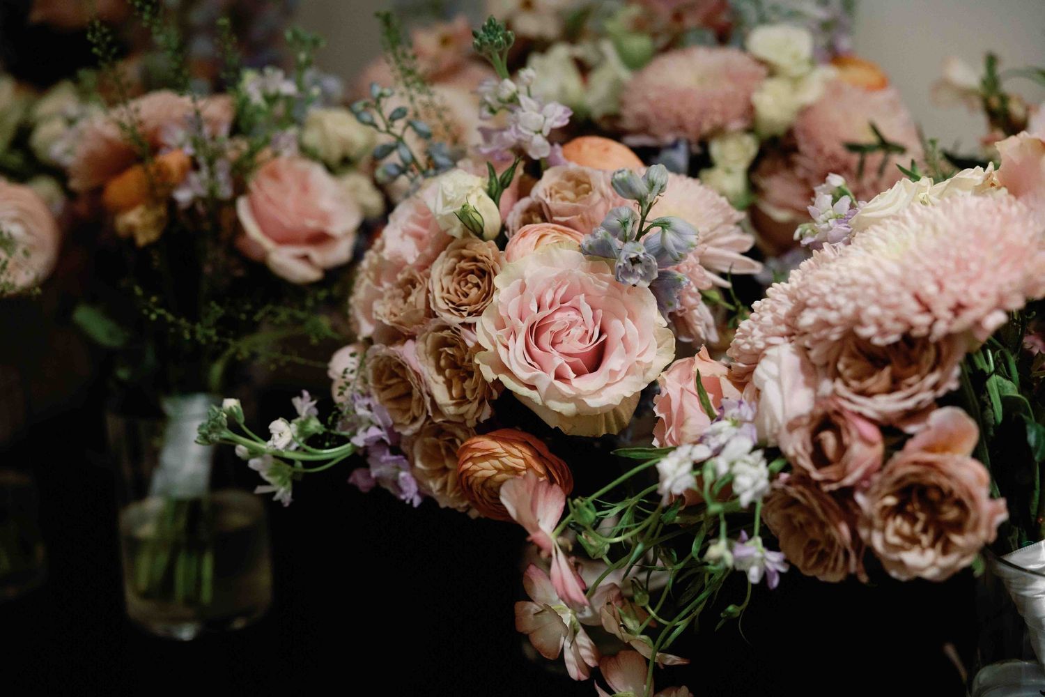 Delicate arrangement of pink and blush roses with greenery for wedding decor.