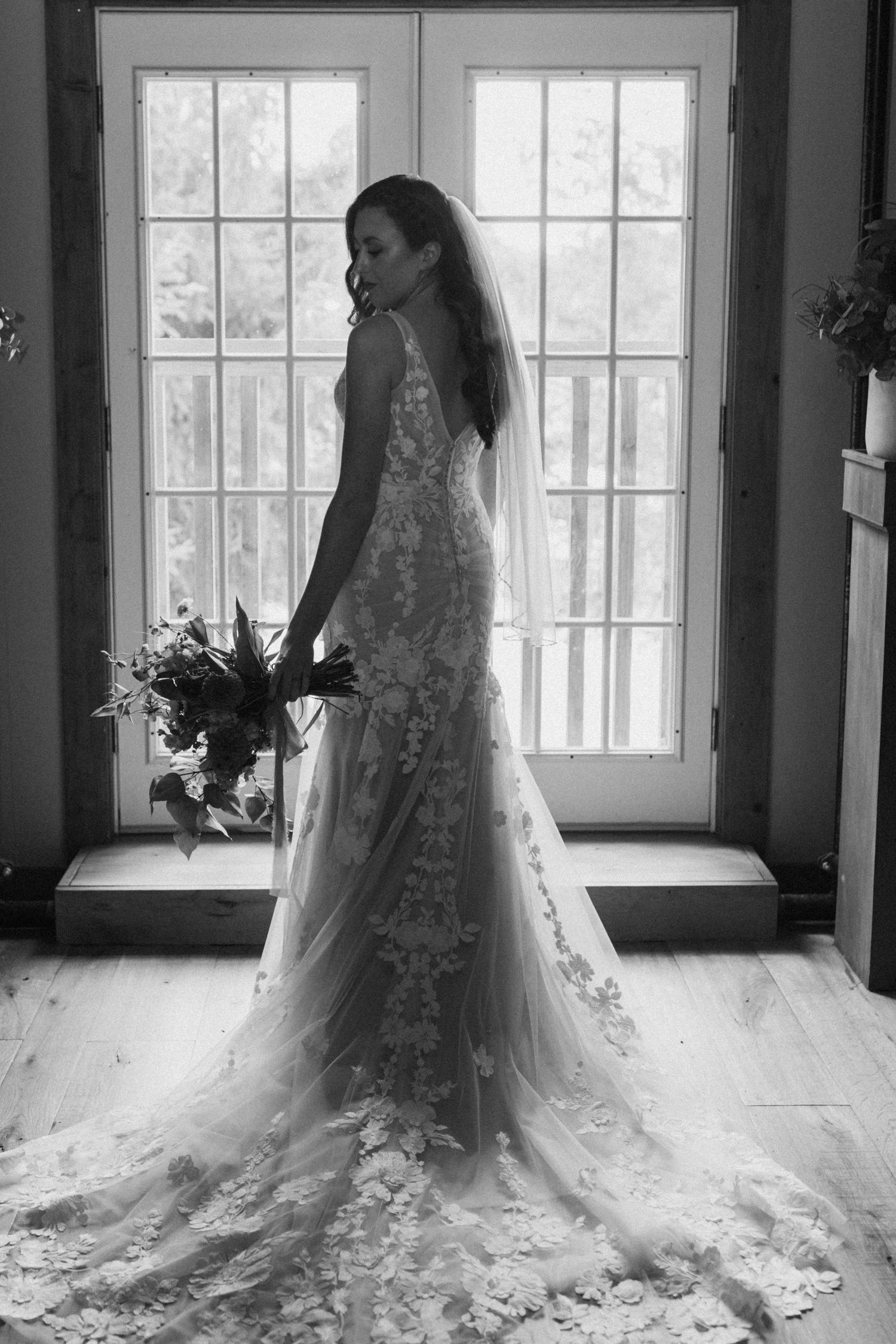 Elegant lace wedding dress with long train photographed against bright windows.