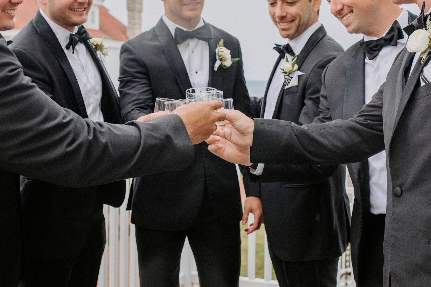 Groomsmen in black tuxedos toasting with champagne glasses.