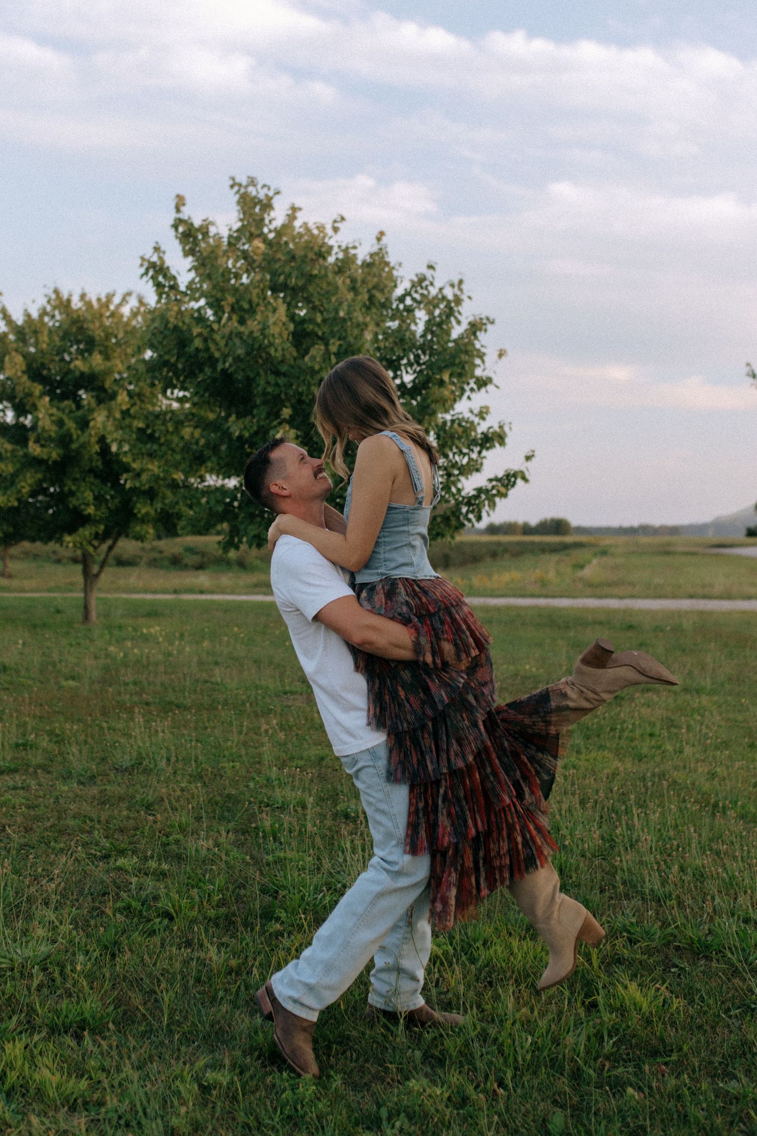 A playful dance scene unfolds in a grassy field with trees in the background.