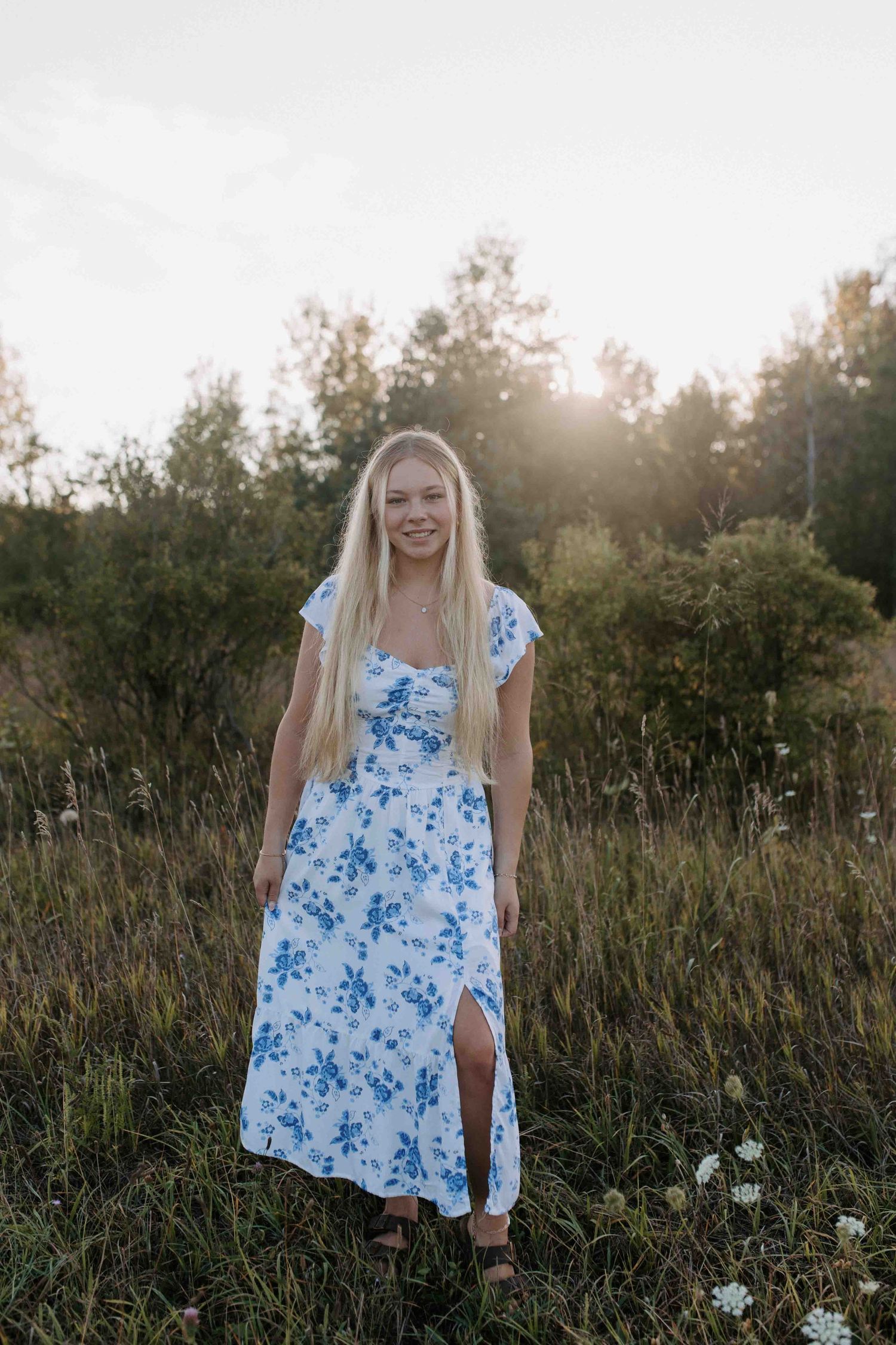 Sunset photoshoot in a meadow wearing a blue floral dress.