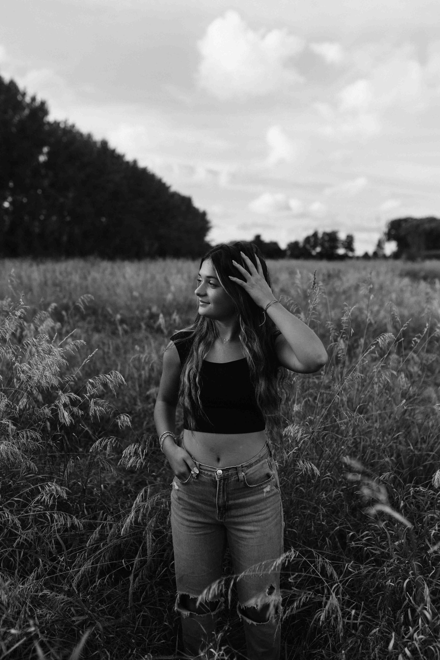 Black and white portrait in field wearing casual denim and crop top.