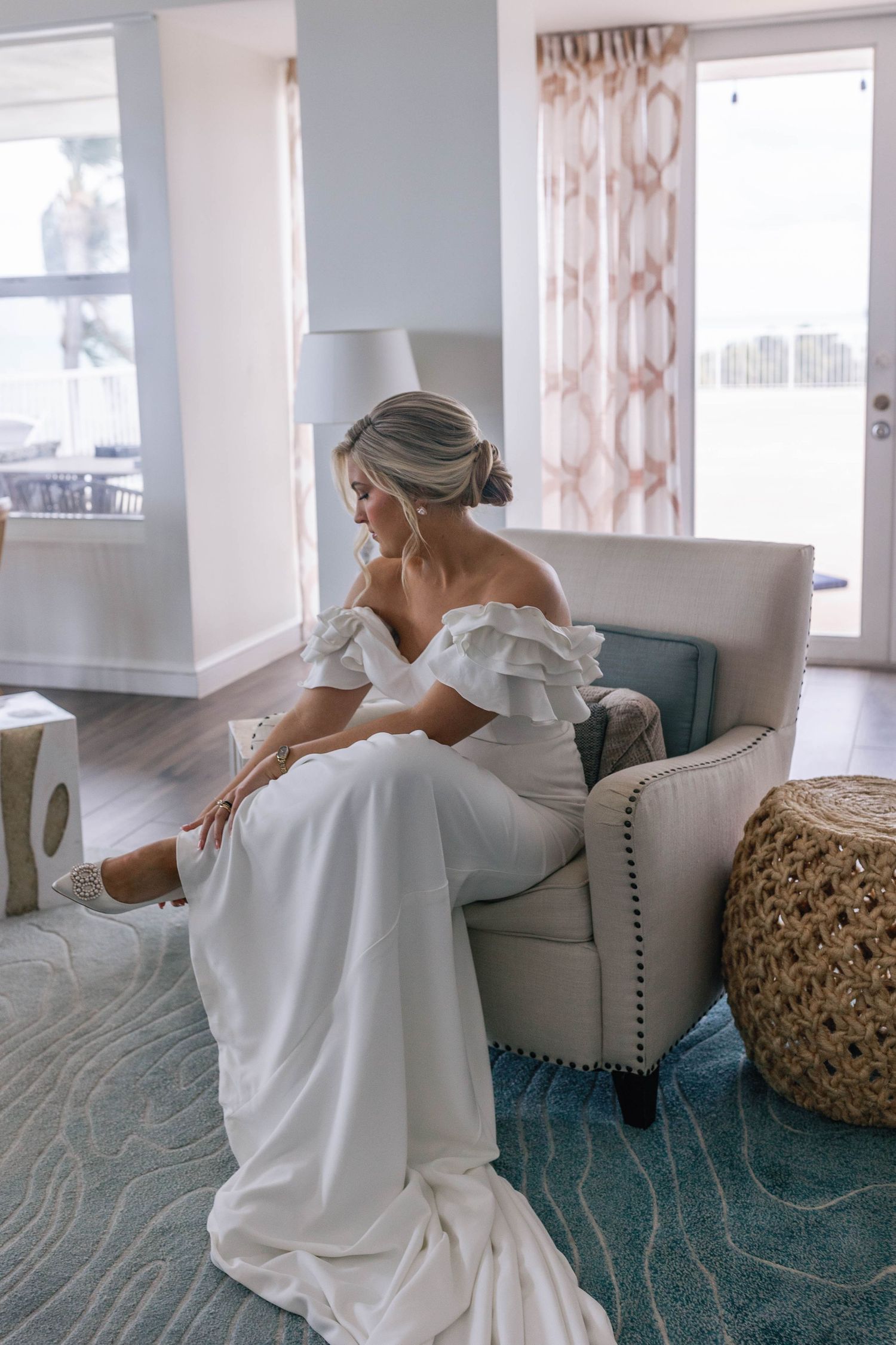 A person in a white robe lounges on a blue carpeted floor in a bright, sunlit room with modern decor.