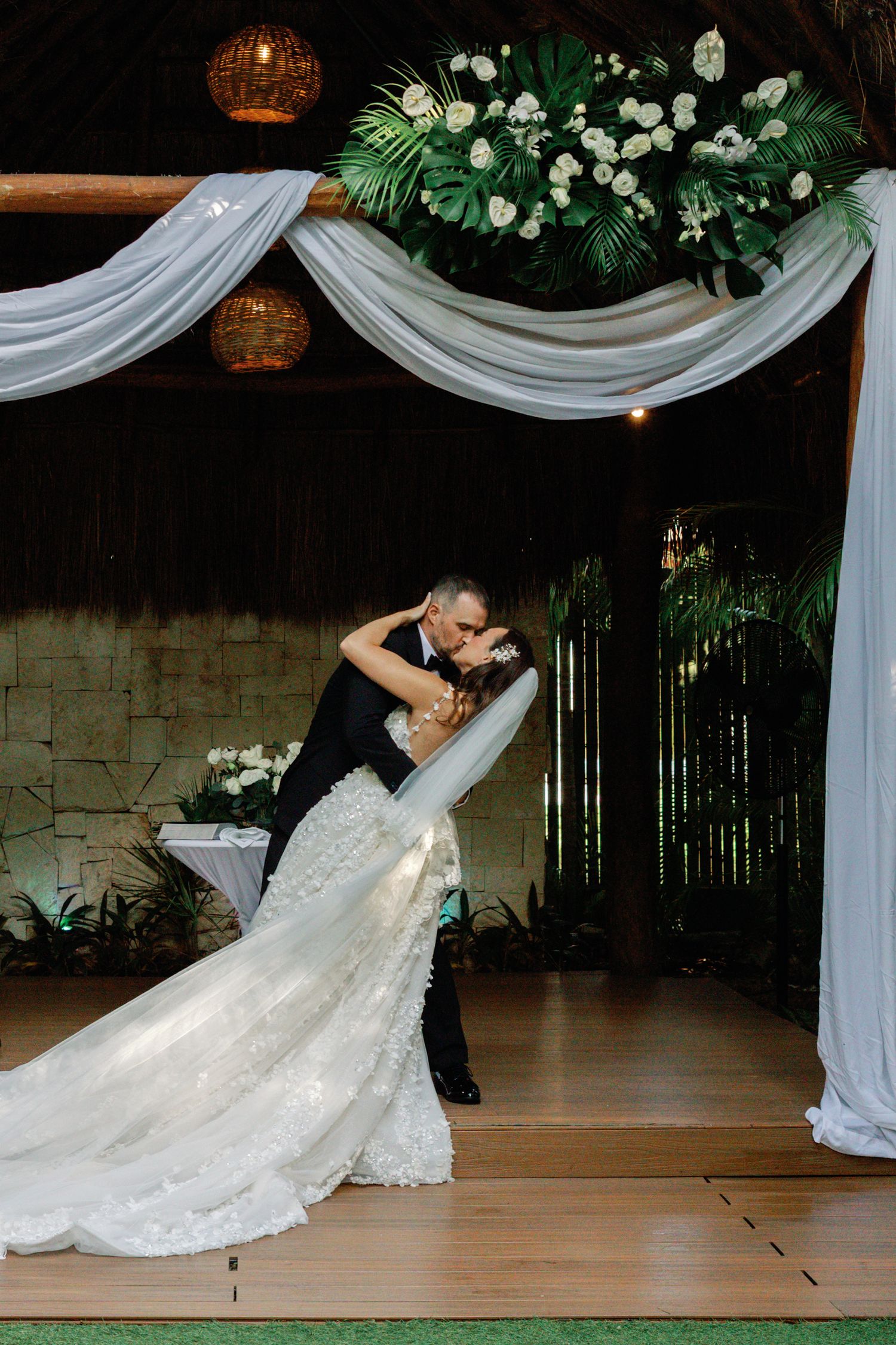 Couple performs romantic dip during first dance at elegantly decorated wedding reception.