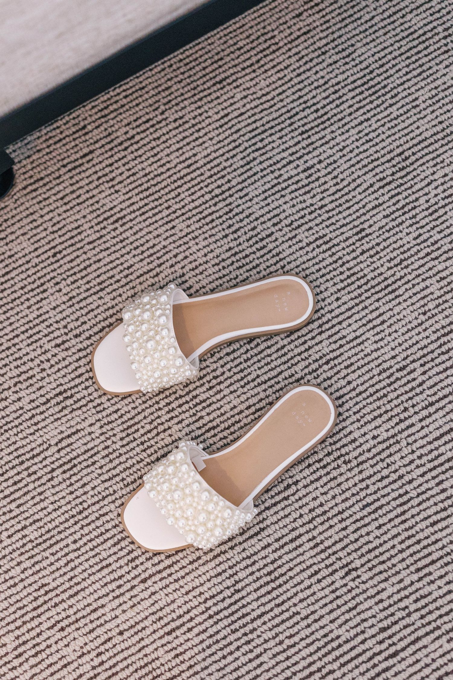 White pearl-embellished bridal slides on striped carpet.