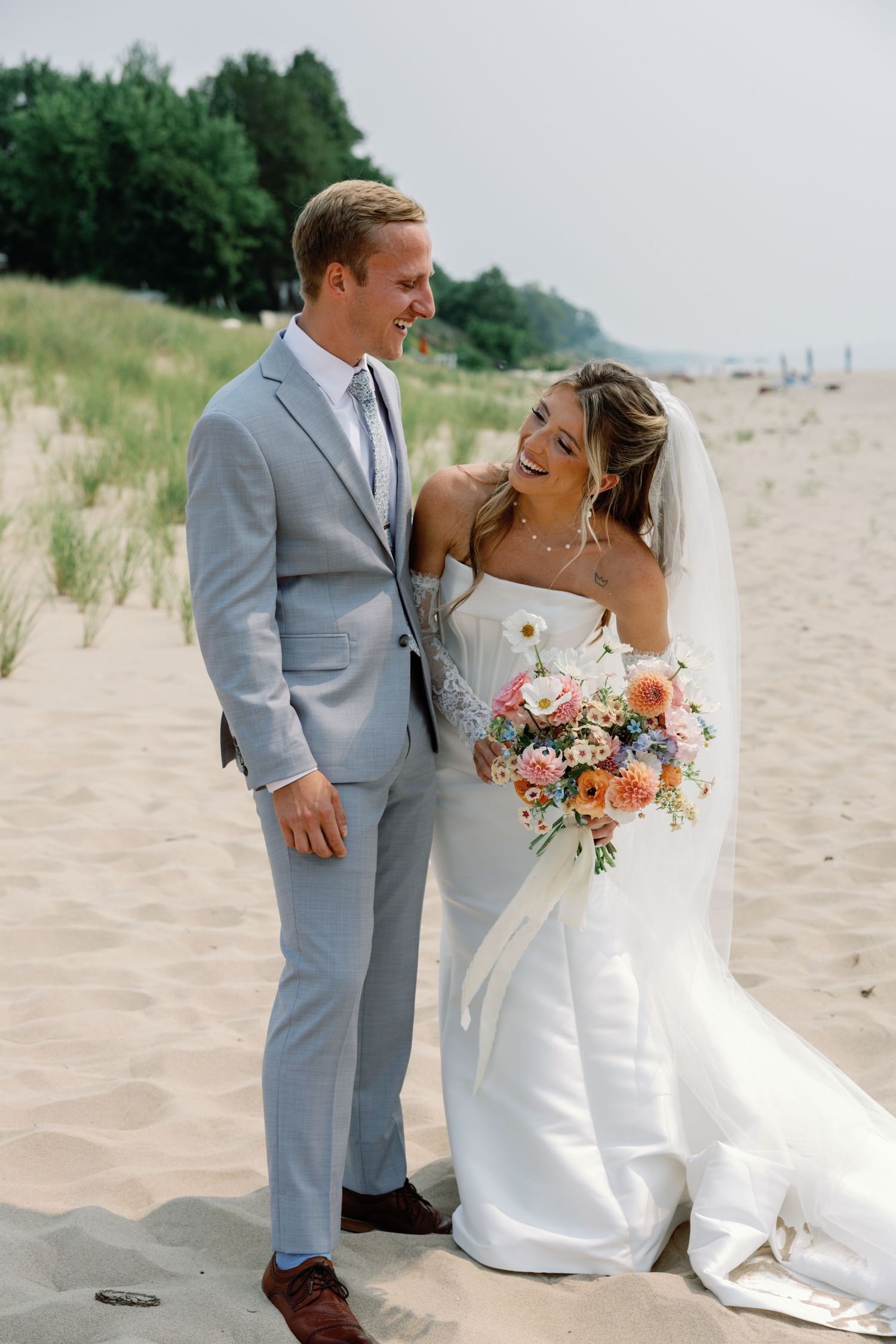 Romantic beach wedding portraits with couple in gray suit and white dress.