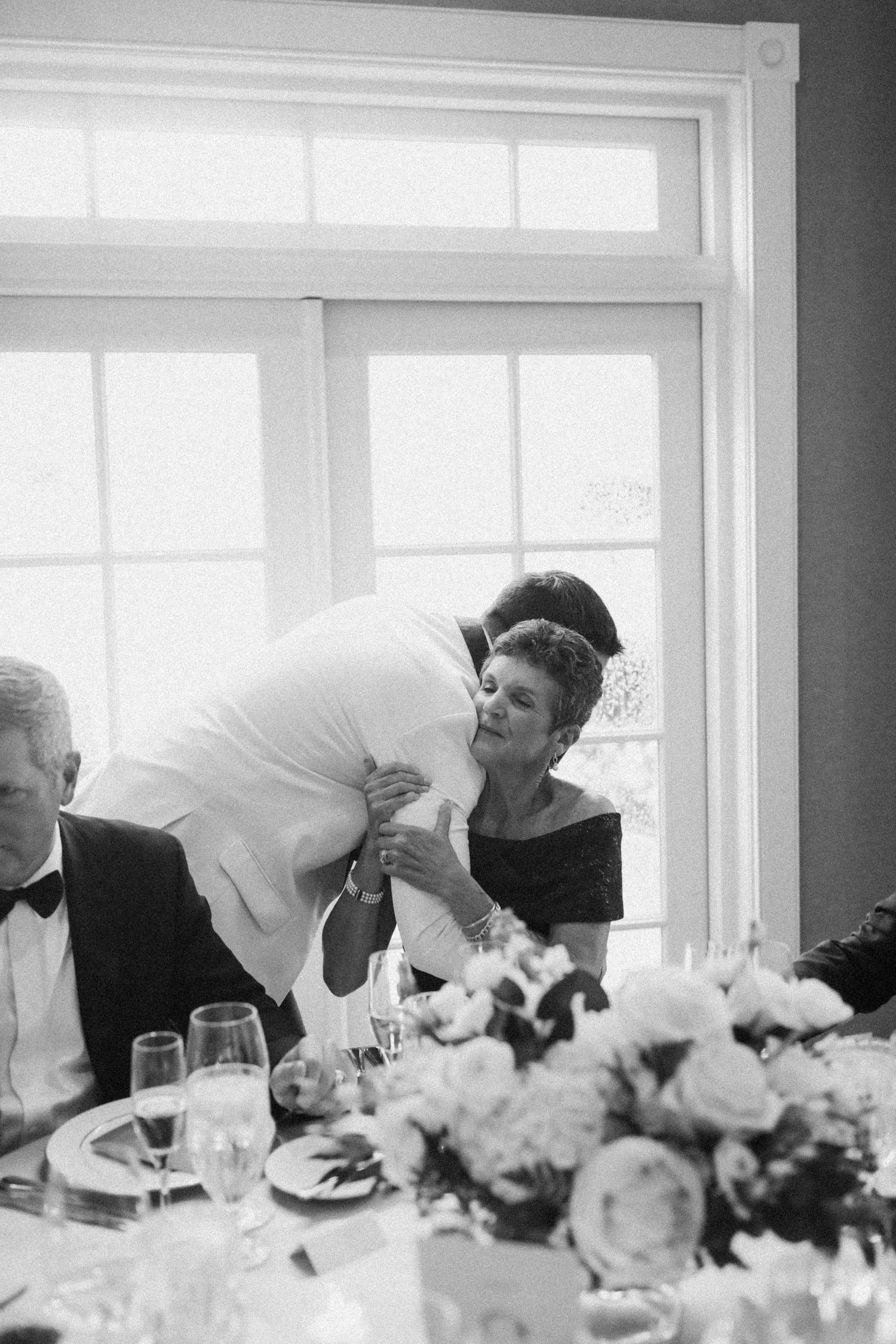 Black and white photo of guests sharing a candid moment at an elegant wedding reception.