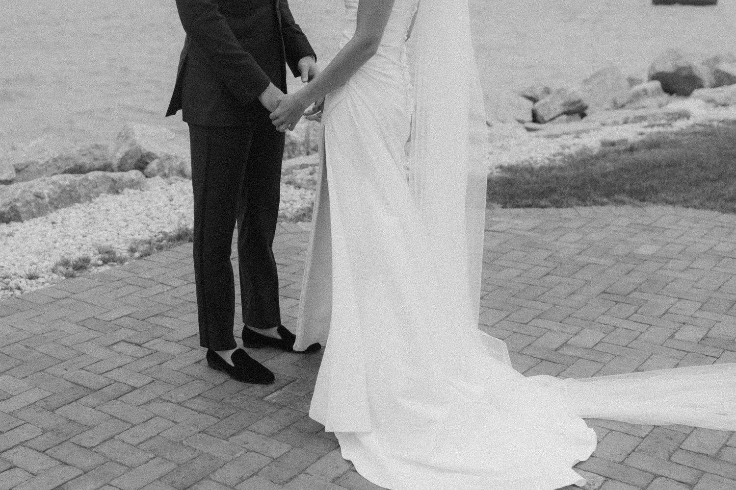 Wedding couple shares intimate dance moves on brick pathway by the water.