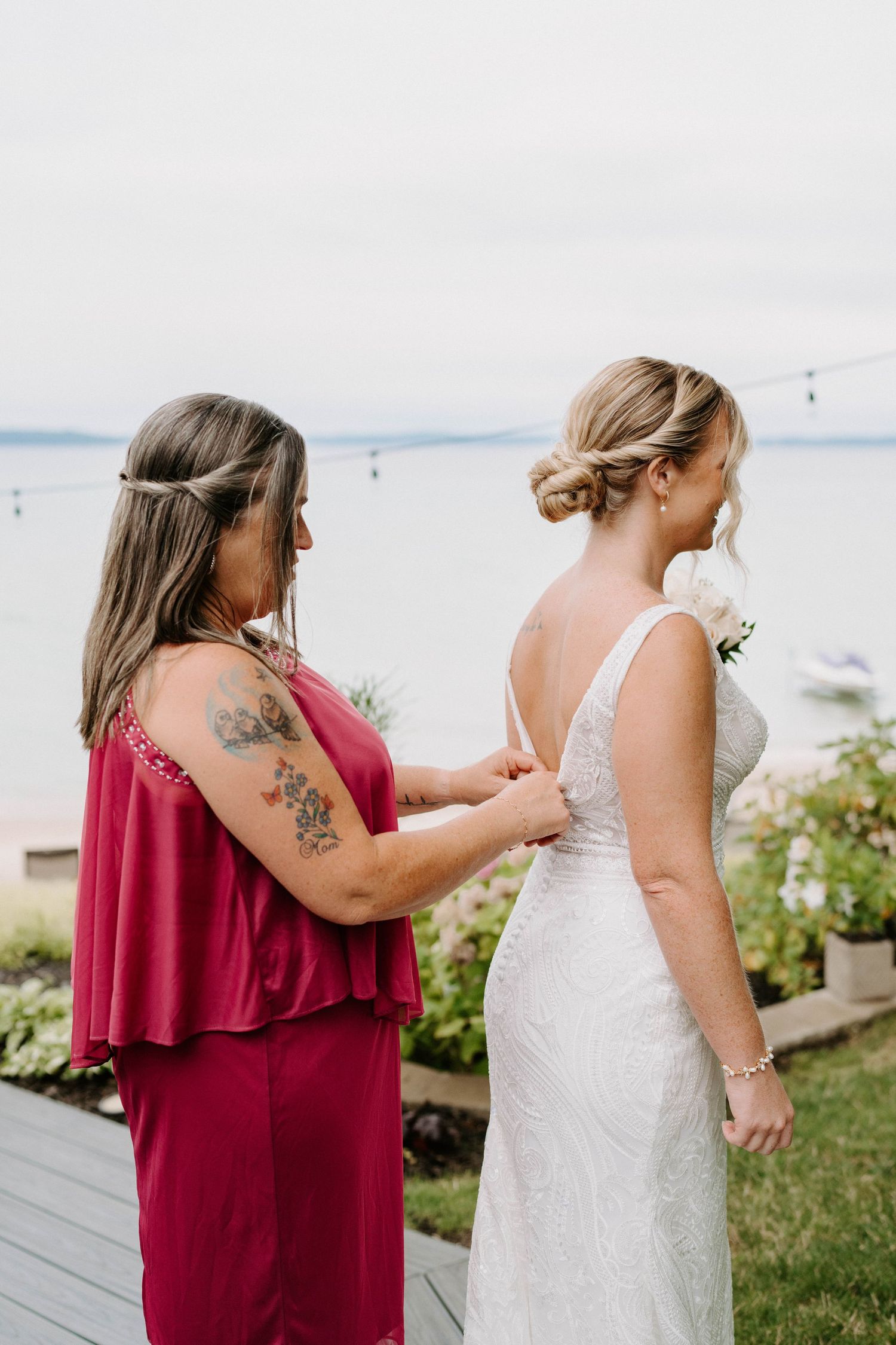Final dress adjustments being made outdoors with water views in the background.