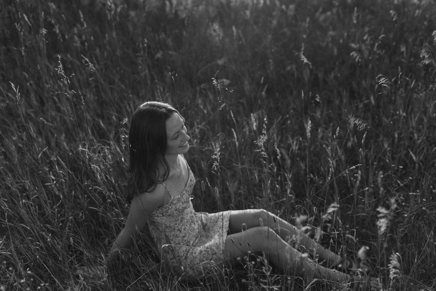 Silhouetted figure in a field of tall grass during golden hour.