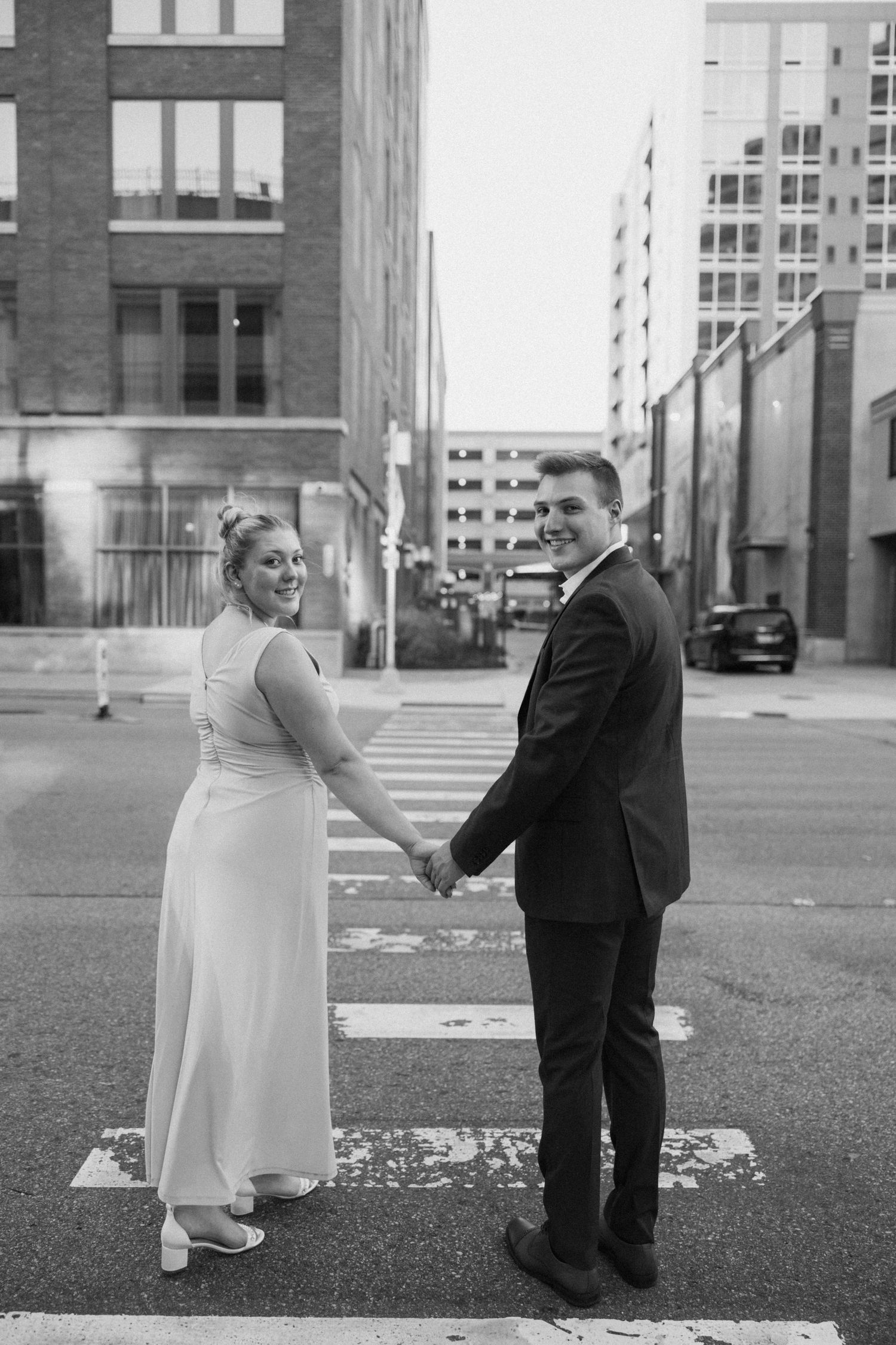 Black and white engagement photos in front of brick buildings downtown.