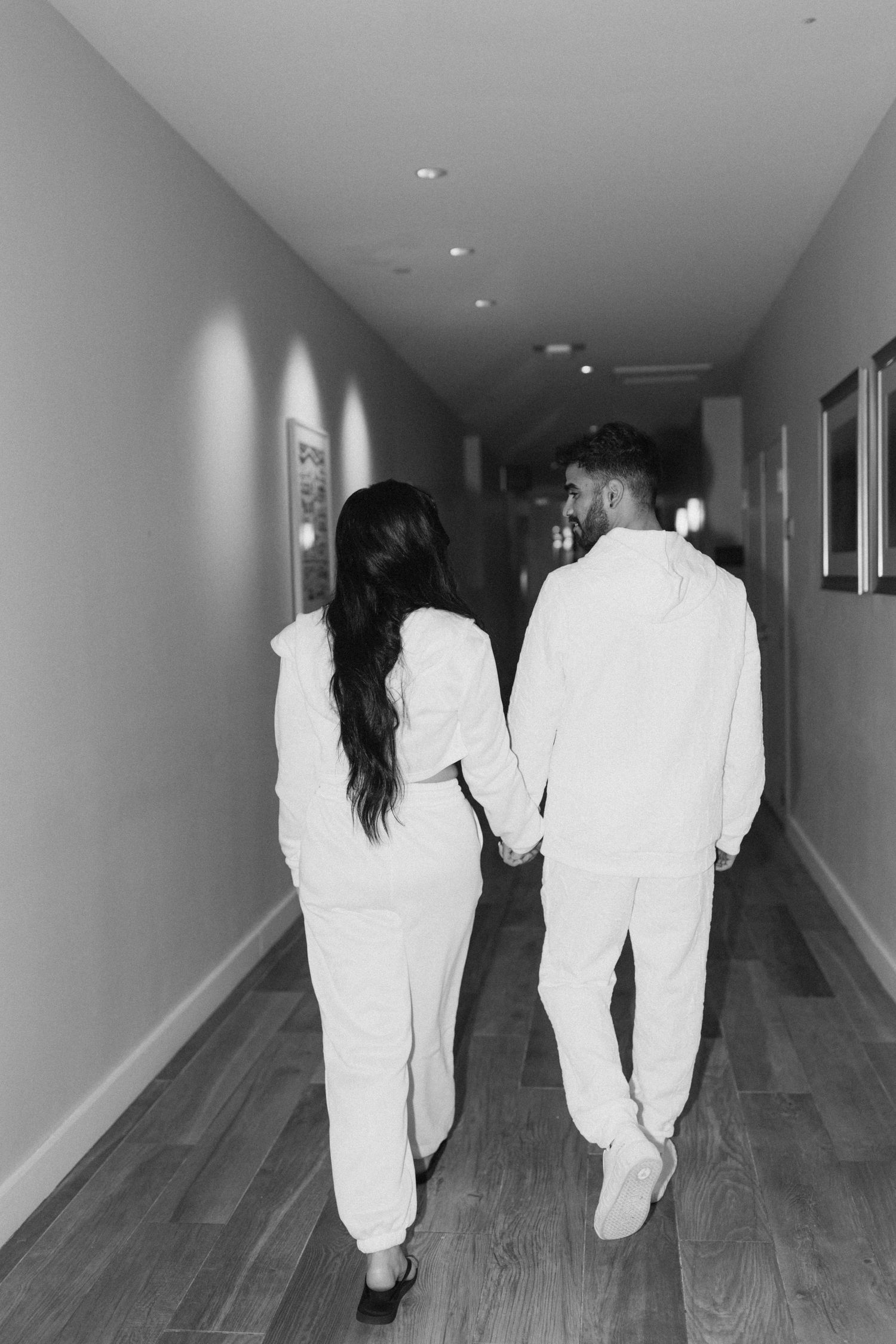 Black and white hallway scene showing people walking away in matching white outfits.