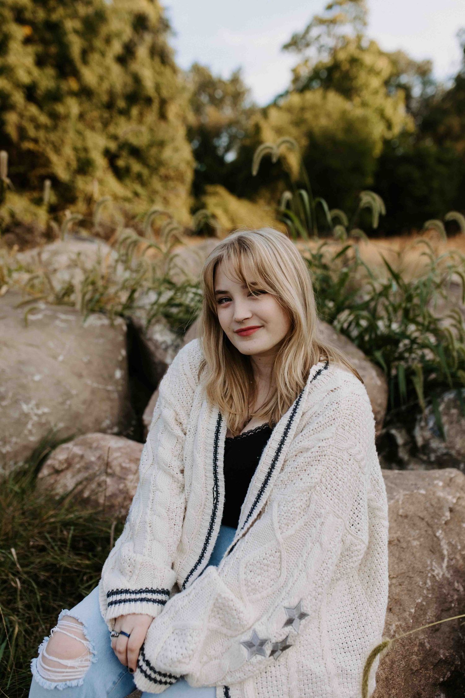 Cozy cream knit sweater worn in autumn outdoor setting with golden sunlight.