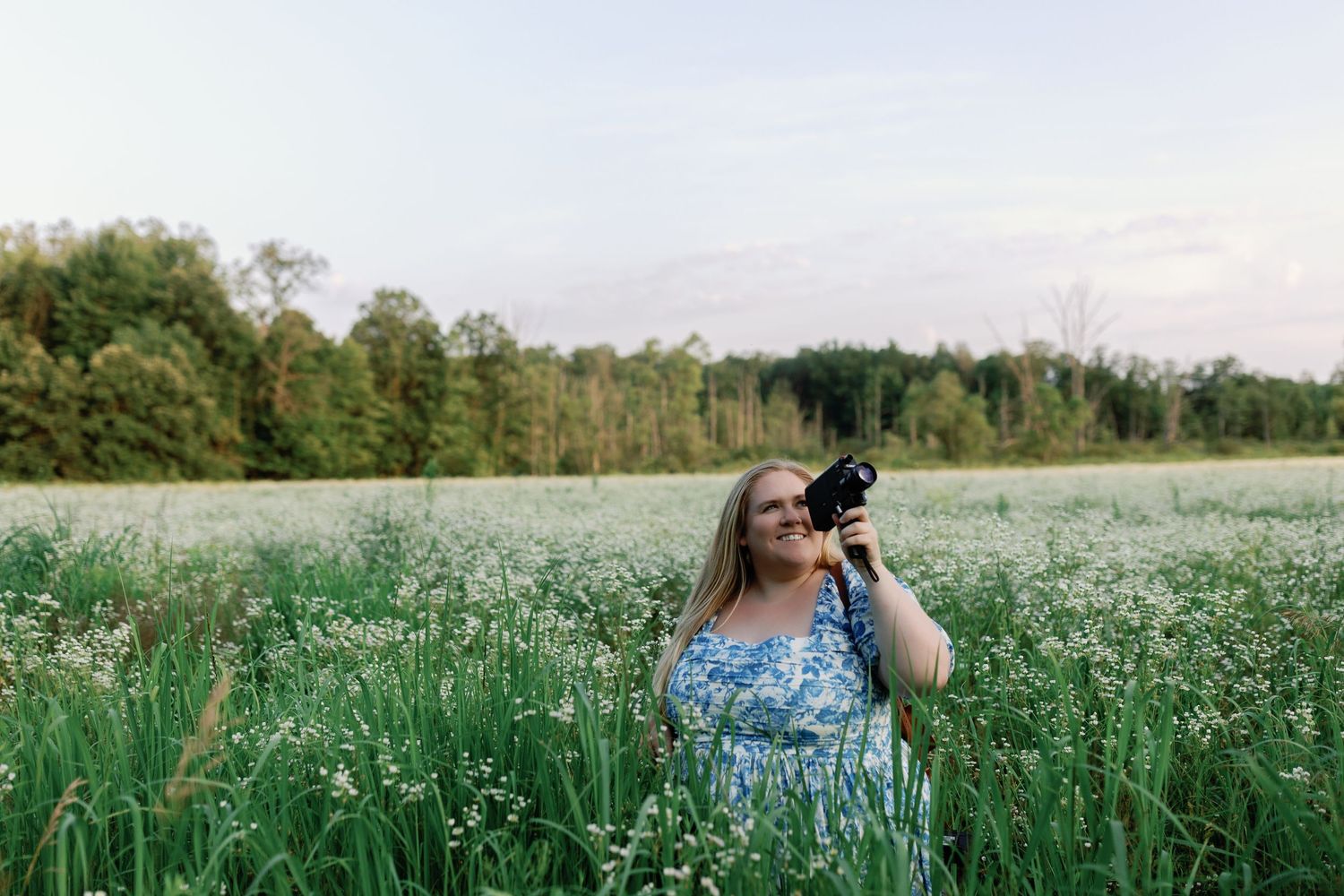 Photographer taking pictures in a blooming white flower field at sunset.
