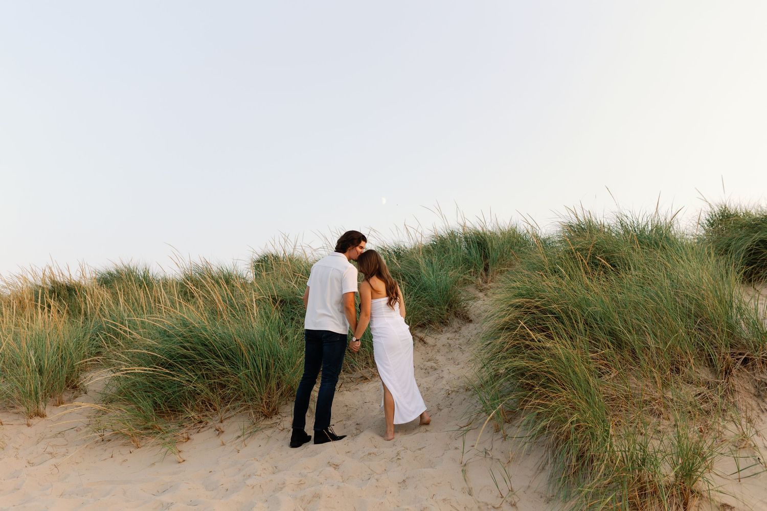 Romantic sequence of two people walking through coastal sand dunes.
