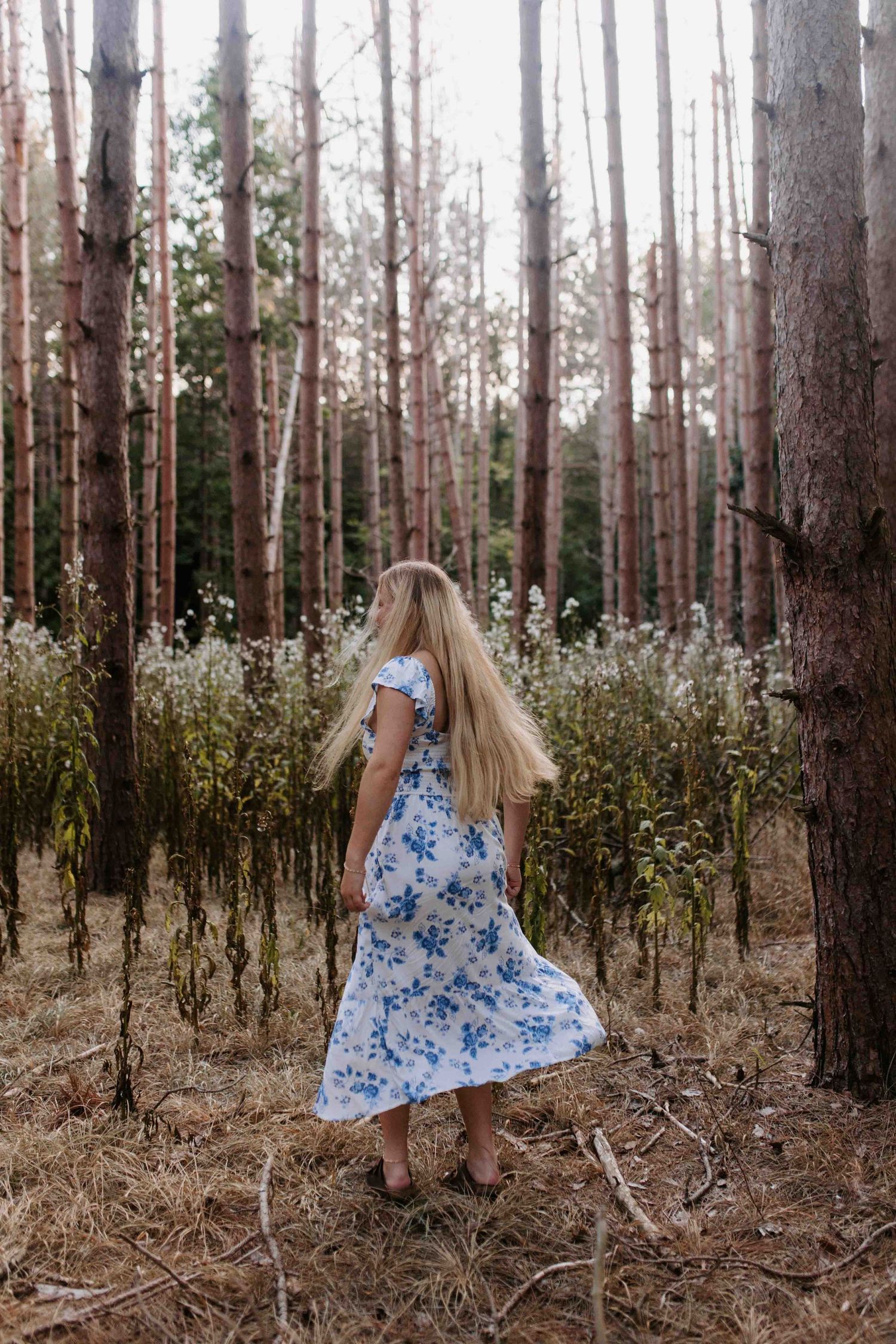 Dynamic fashion shot of a flowing blue dress against a forest backdrop.