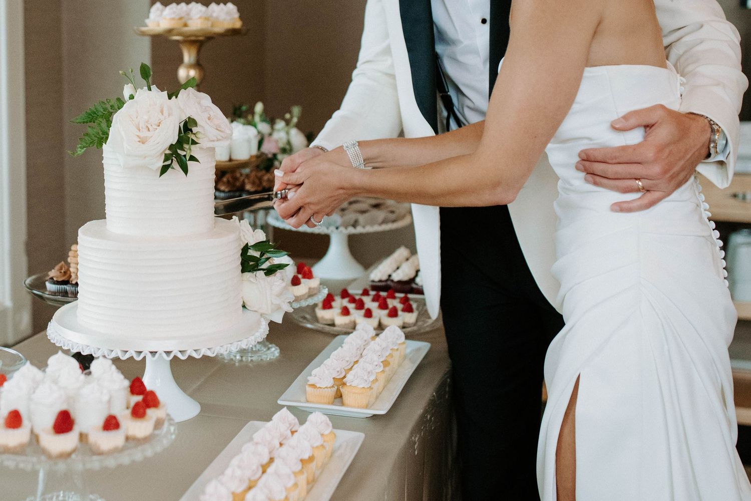 Wedding dessert table featuring elegant white cakes and strawberry treats arranged on tiered stands.