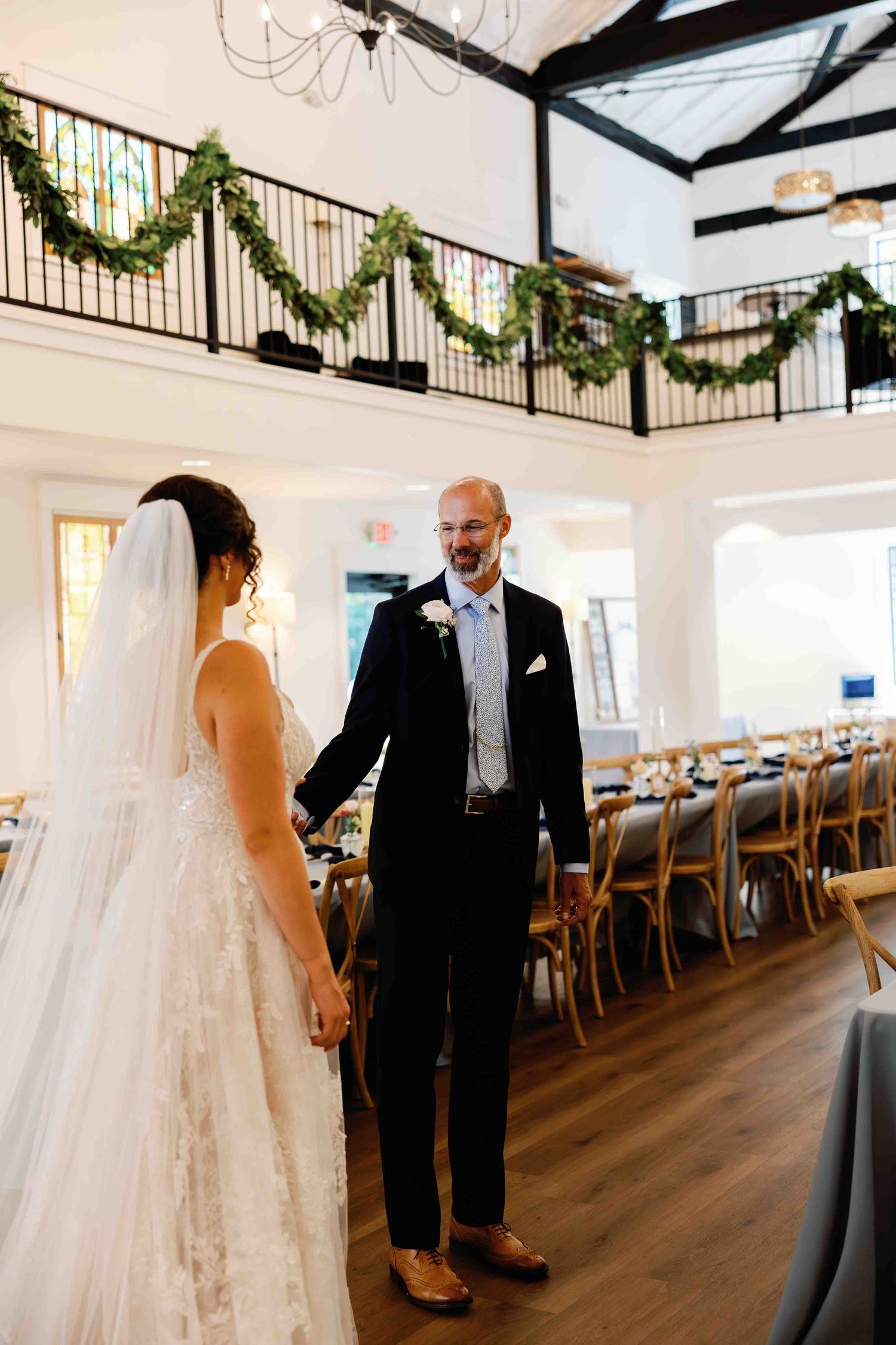 Wedding reception venue with white tablecloths and festive garland decorations hanging from the ceiling.