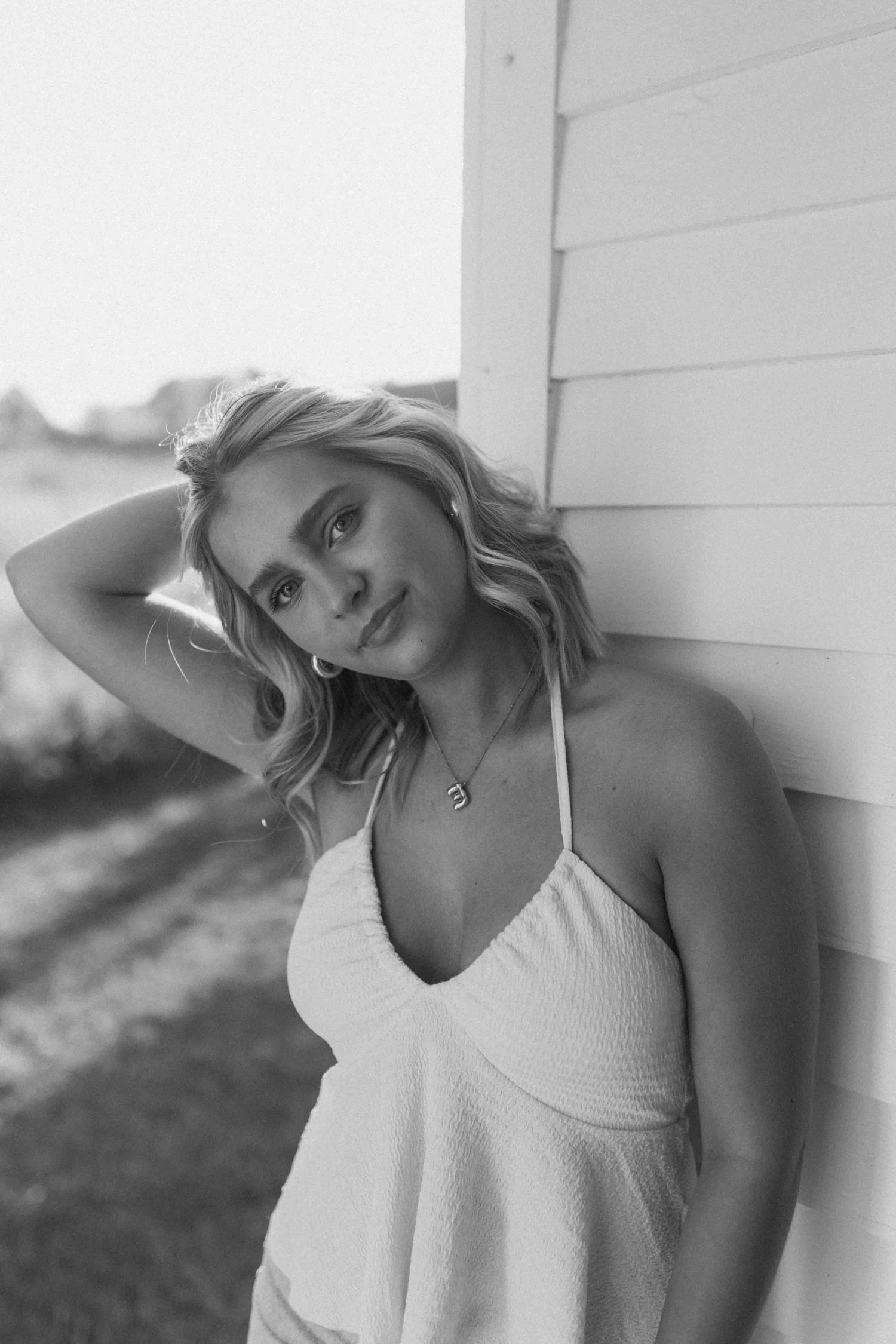 Black and white portrait showing relaxed casual pose against wall.